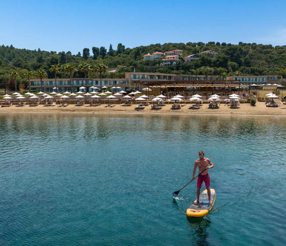 Man paddleboarding in front of the Miraggio Resort beach