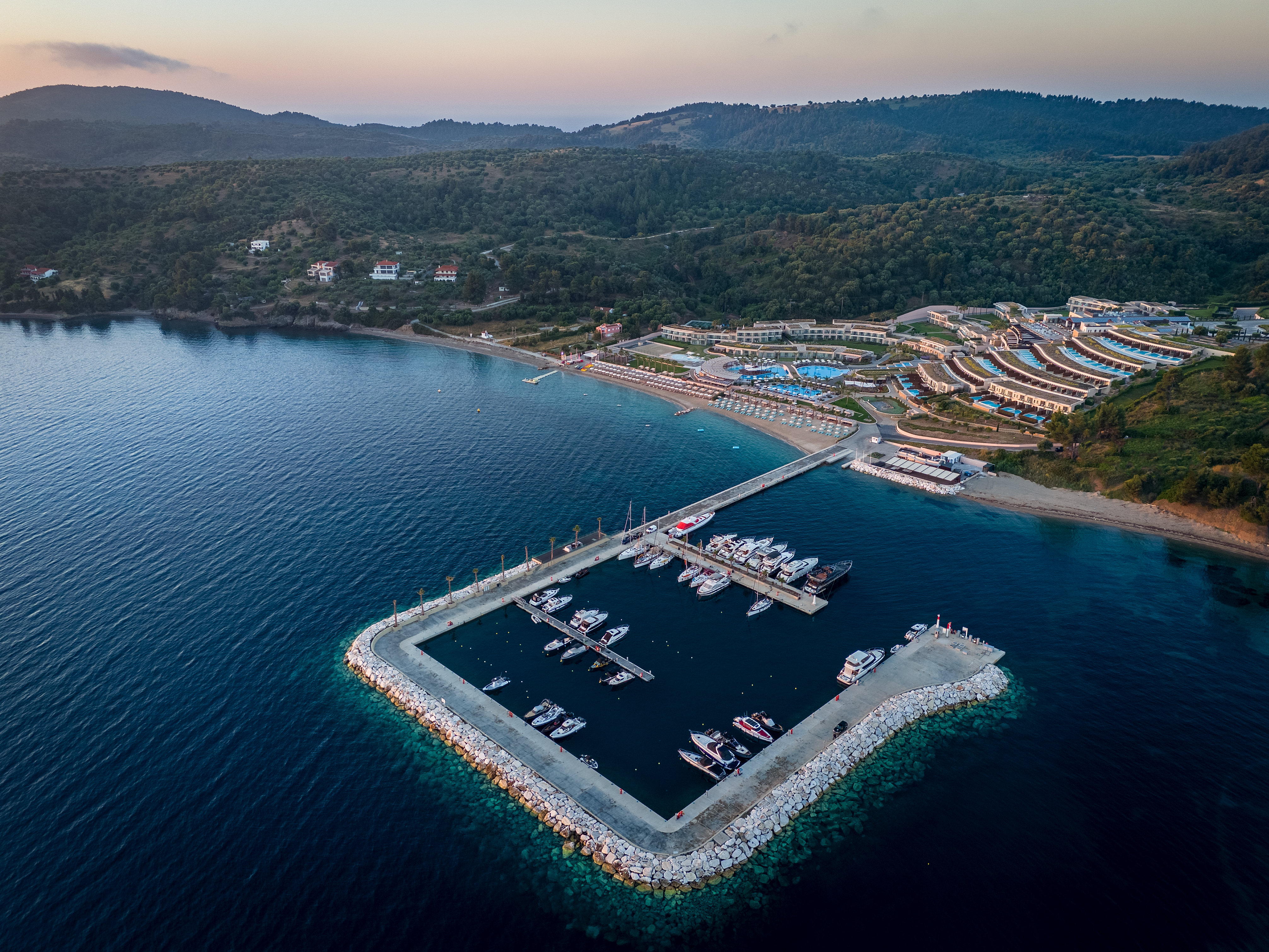 Aerial view of Miraggio Thermal Spa Resort and its private marina surrounded by clear blue waters and lush hills