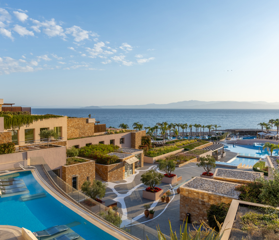 Panoramic view of the resort's terraced architecture, infinity pools, and the Aegean Sea