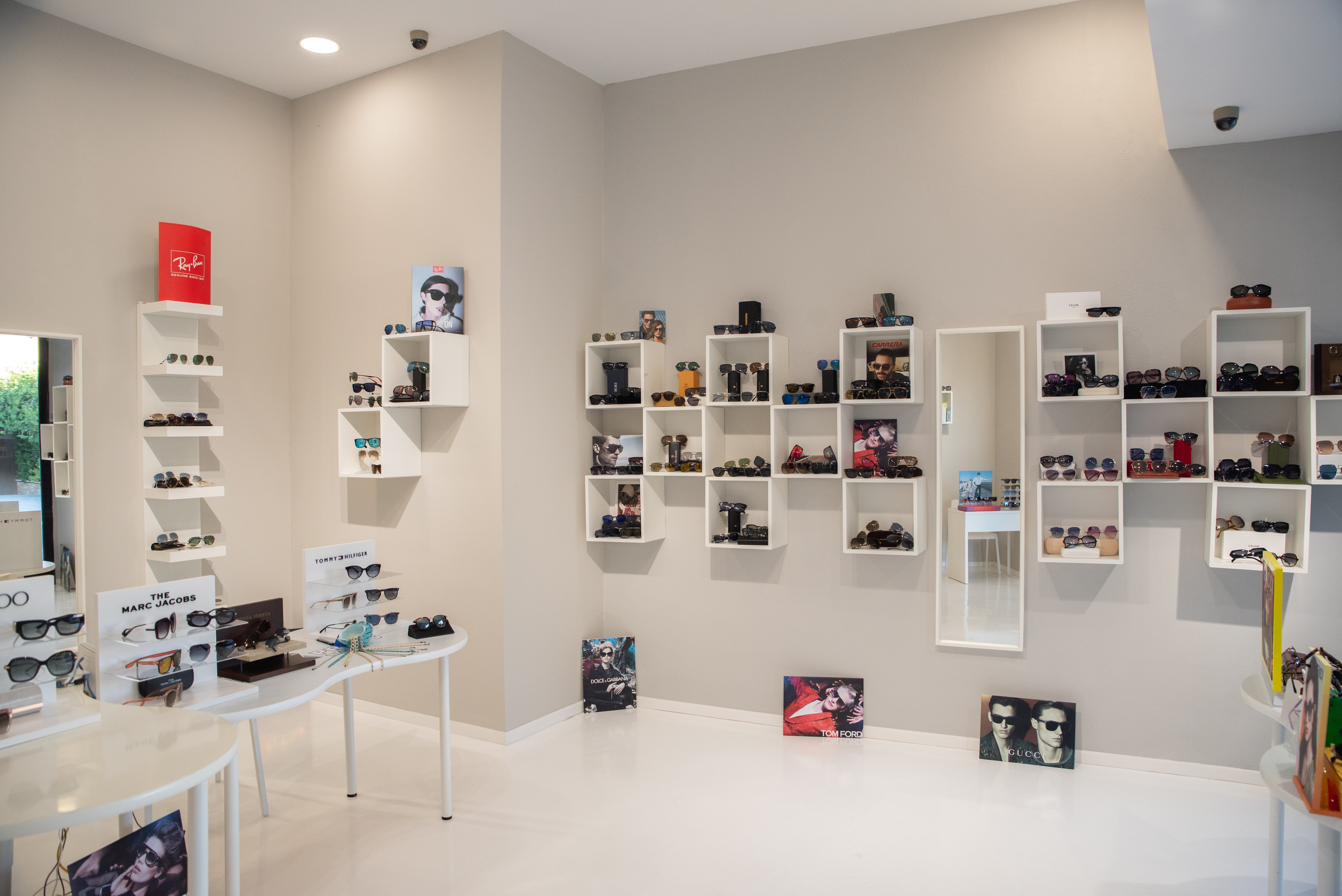 Display of designer sunglasses including Ray-Ban, Gucci, and Dolce & Gabbana on shelves