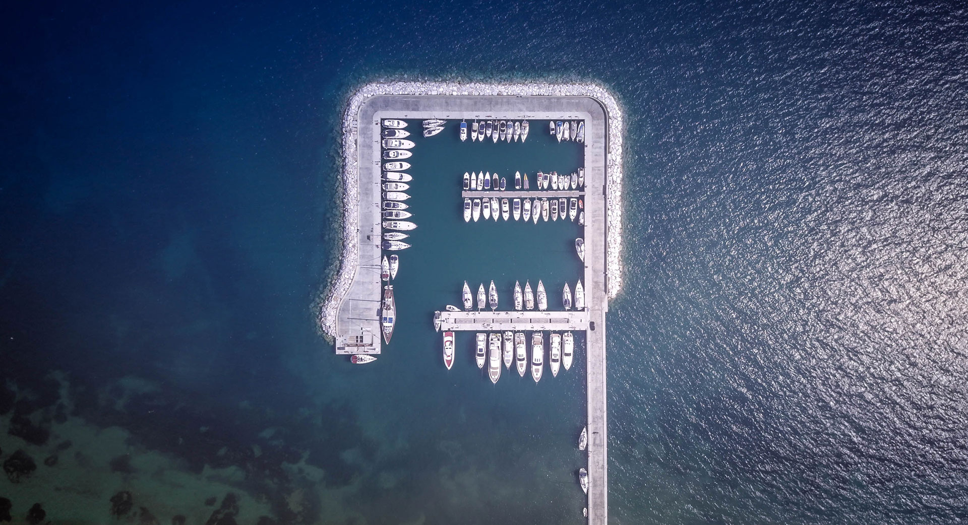 Aerial view of the marina with yachts docked in turquoise waters surrounded by sea