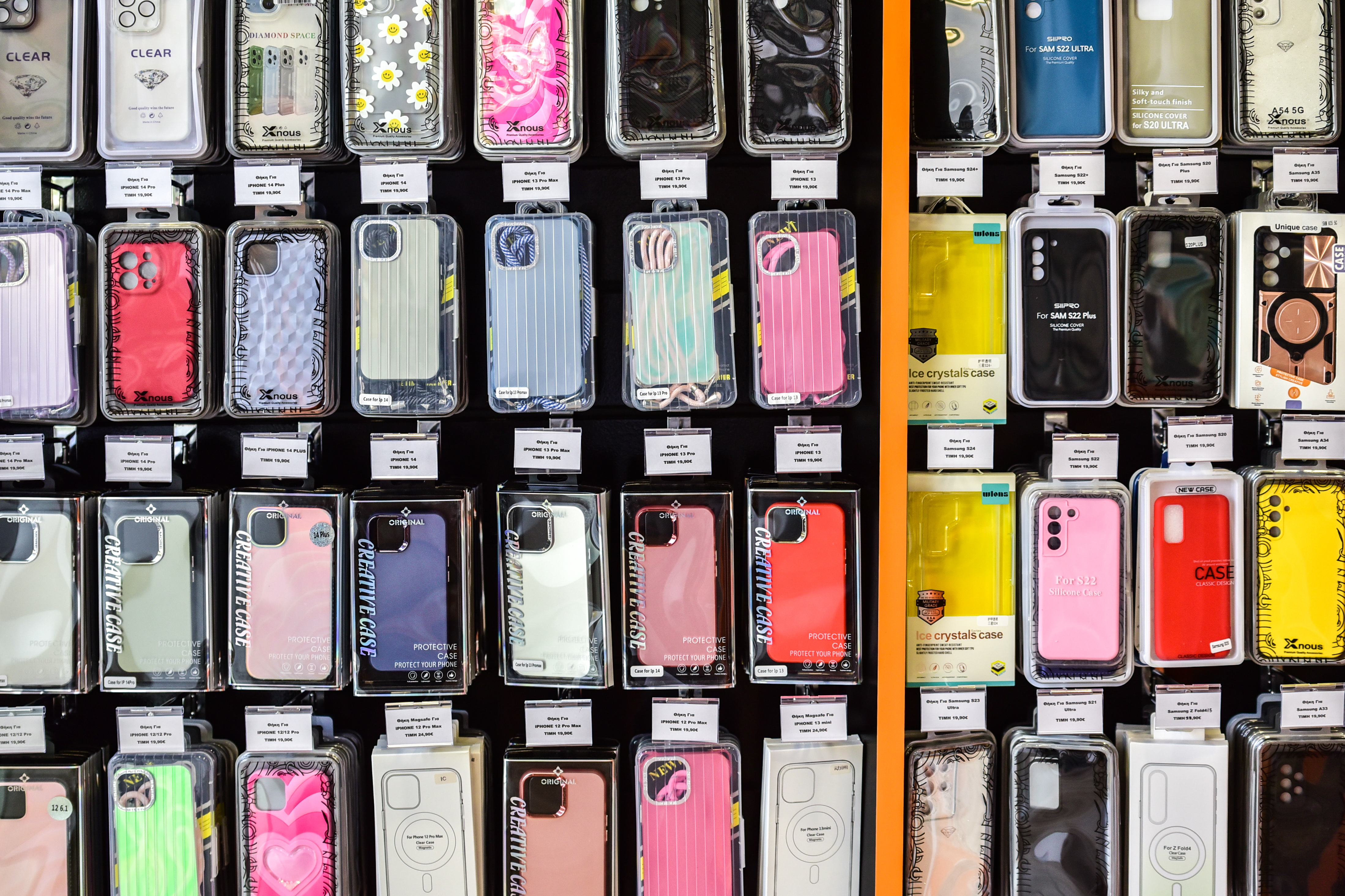 Colorful smartphone cases in various designs and textures displayed on wall