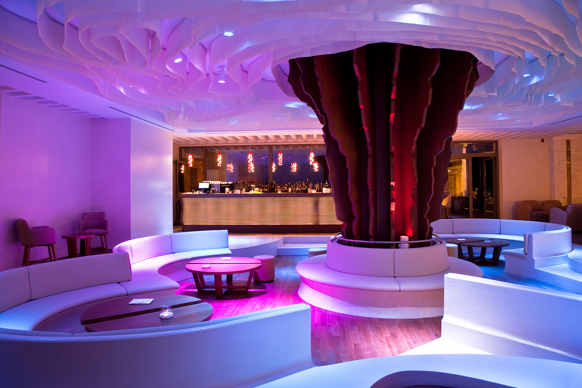 Indoor lobby bar with modern seating, purple ambient lighting and stylish bar counter in the background