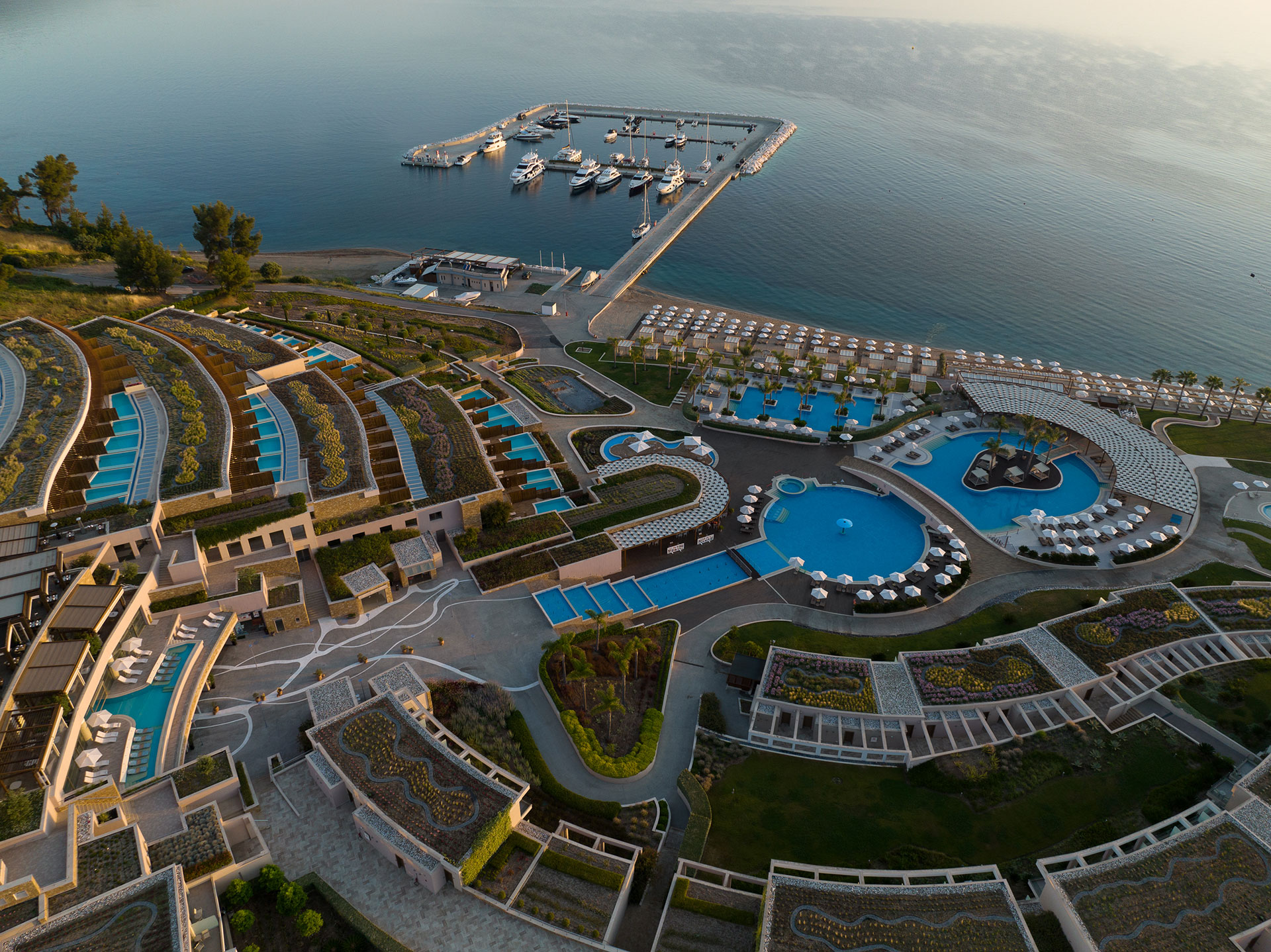 Aerial morning view of the resort's pools, private terraces, and marina by the Aegean Sea