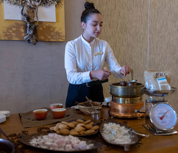 Waitress preparing traditional Greek coffee beside sweets and loukoumi