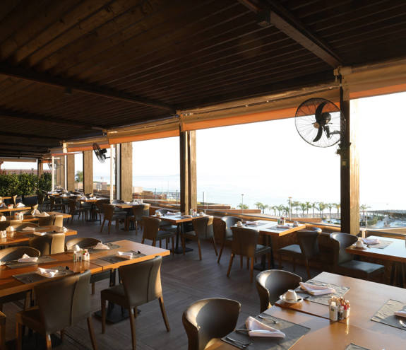 Kritamo restaurant bright exterior with wooden roof, and tables and sea view