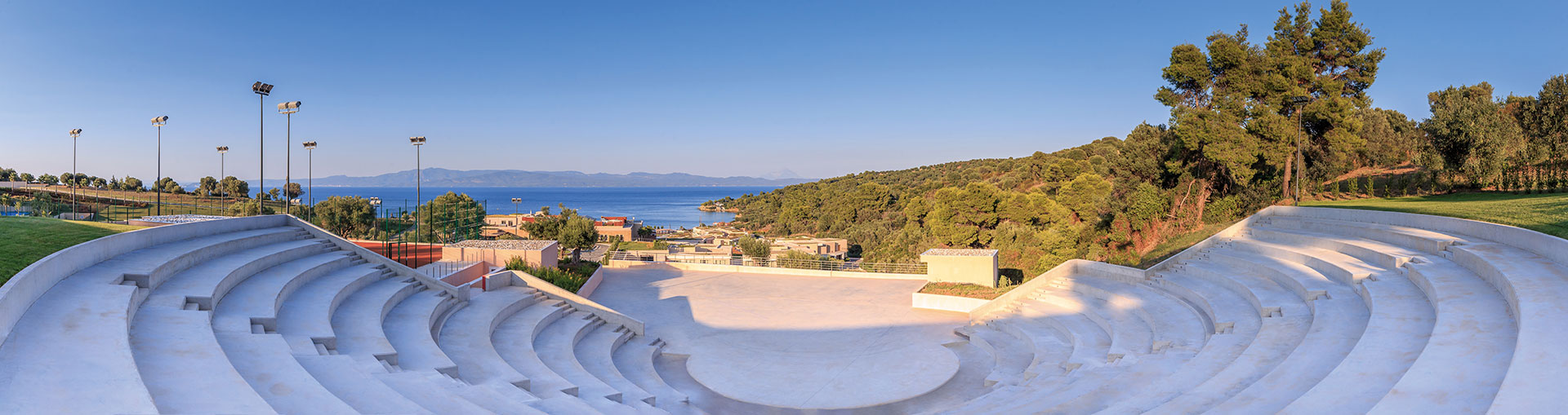 Open-air amphitheater with sea and mountain views surrounded by greenery