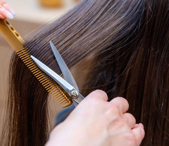 Close up of stylist cutting long brown hair with precision scissors