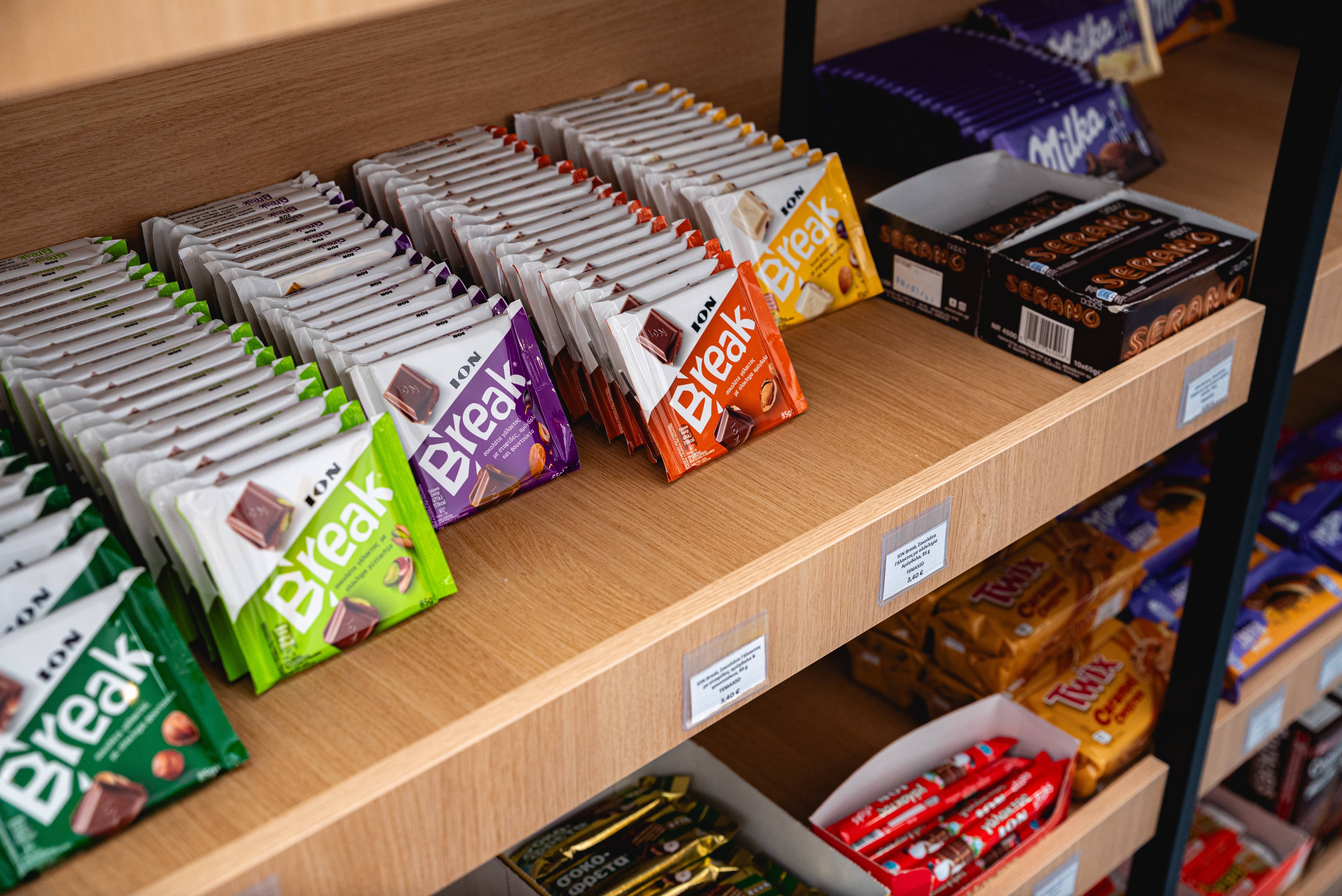 Assorted ION Break chocolate bars and other sweets neatly displayed on wooden shelves