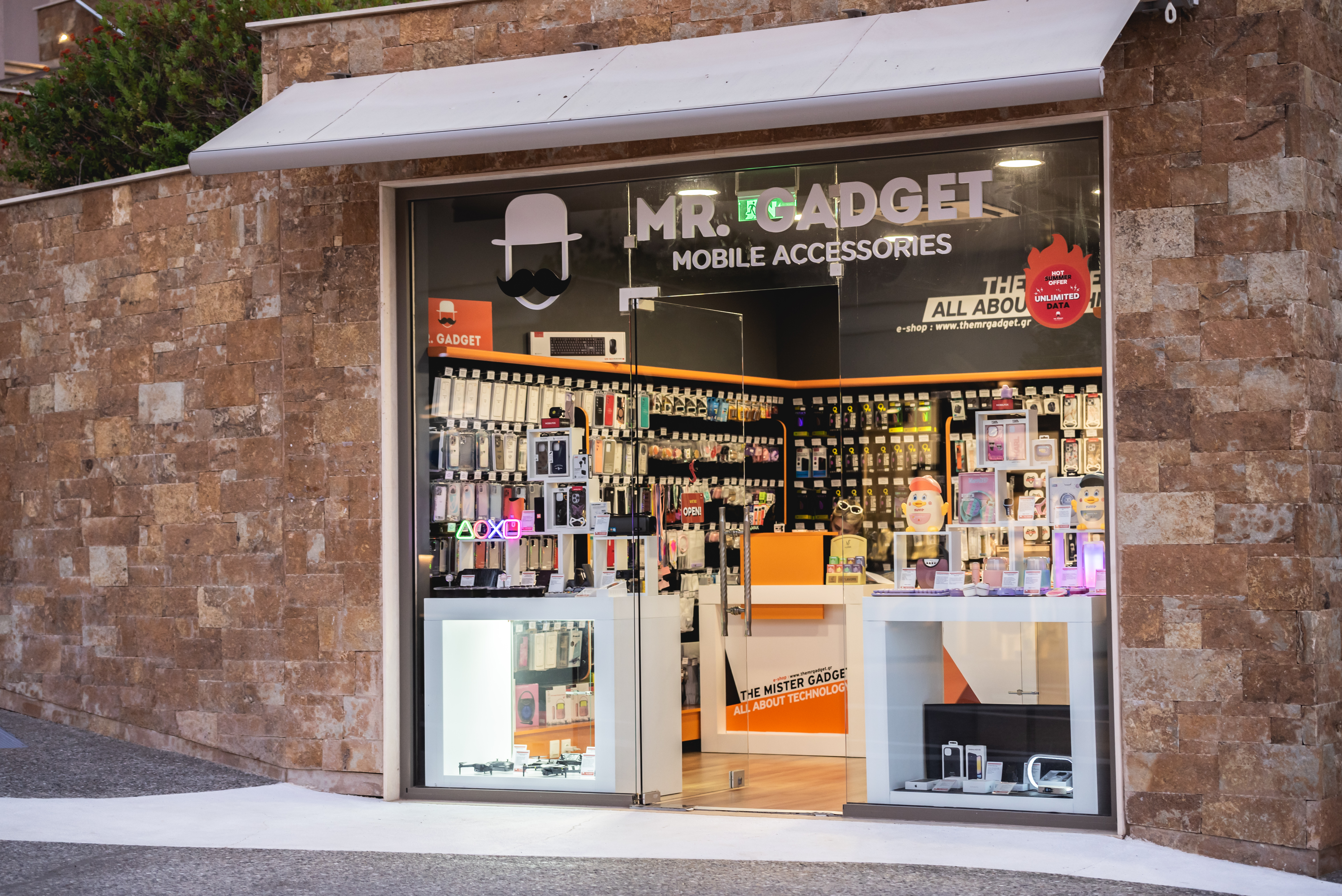 Mr. Gadget shop exterior with modern glass facade displaying colorful mobile accessories and smart tech items