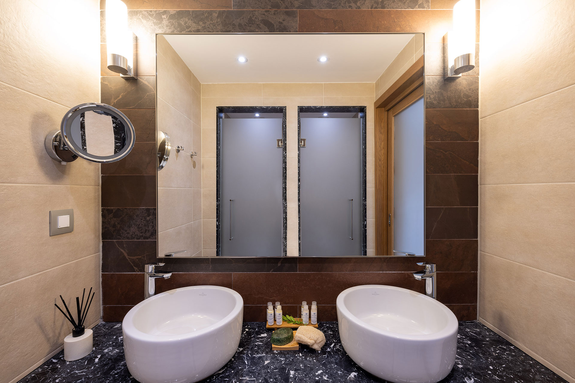 Modern bathroom with twin basins, marble countertop, and frosted glass shower doors