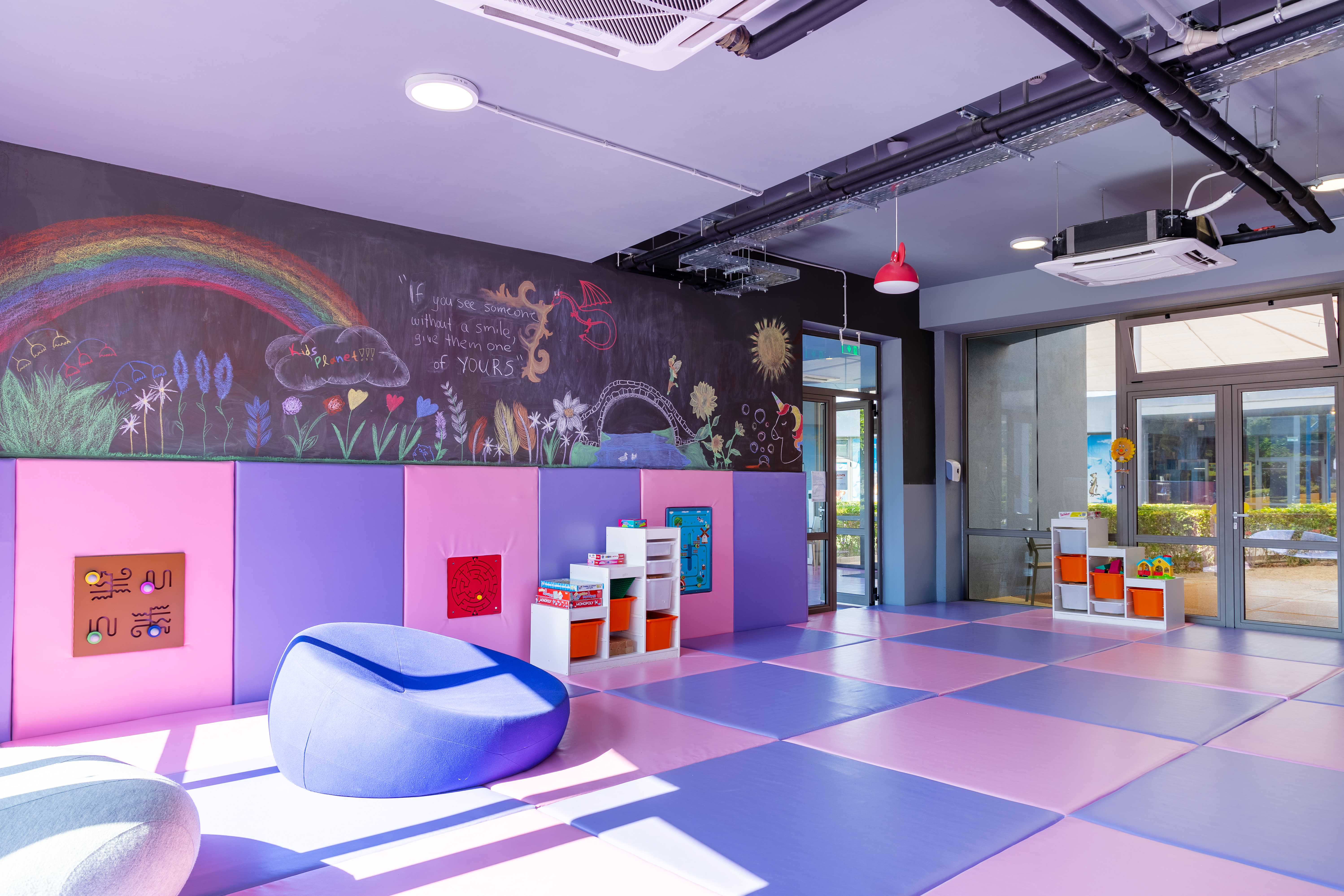 Colorful indoor playroom with soft mats and creative wall art at Kids Planet