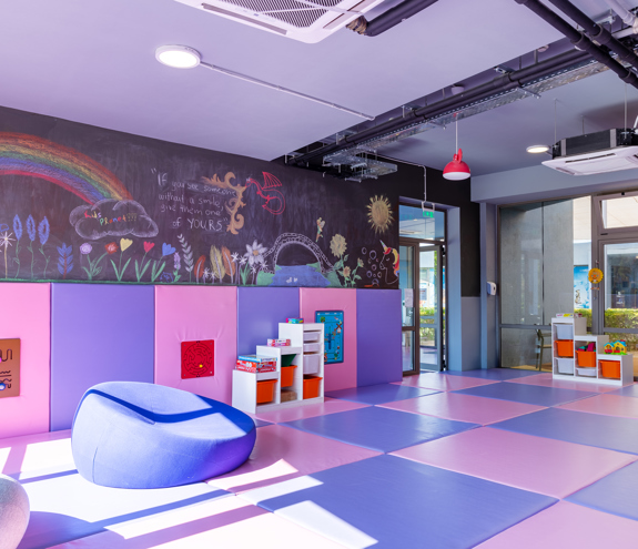 Colorful indoor playroom with soft mats and creative wall art at Kids Planet