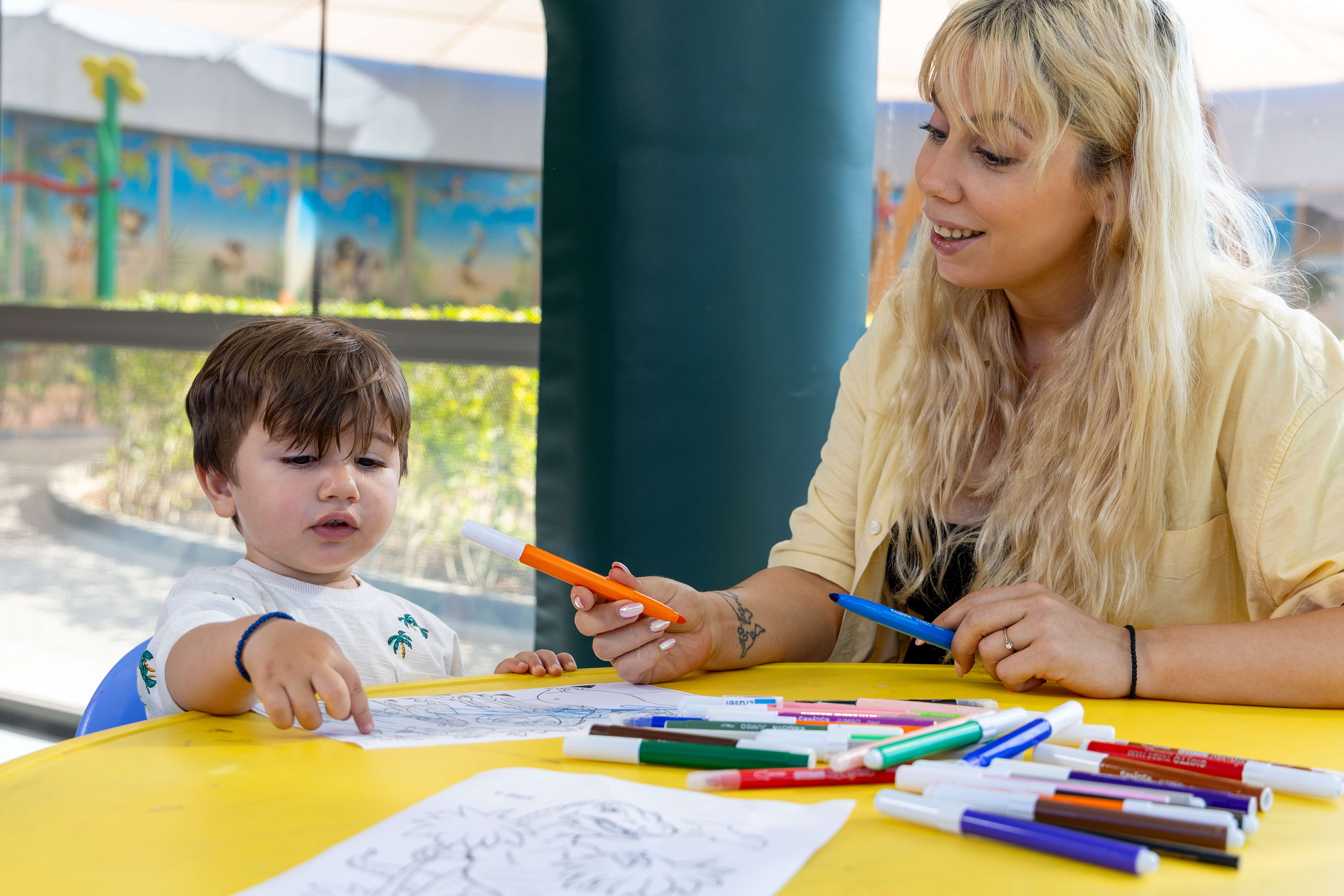 Mother painting on a table with her son in the indoor playground of Kids Planet