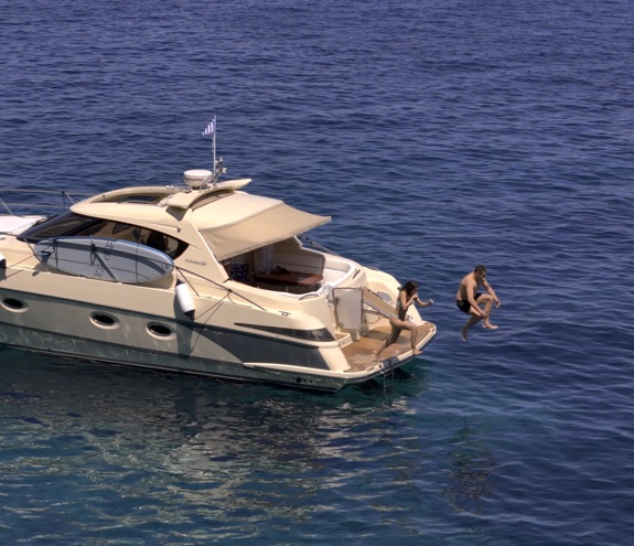 Couple relaxing at the stern of a motor yacht anchored in clear blue water