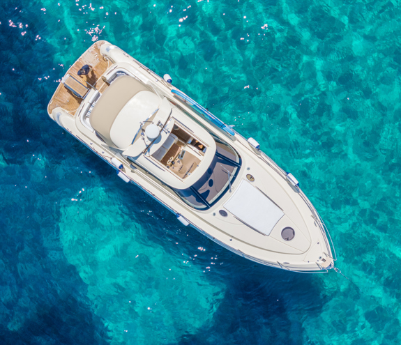 Top-down view of a luxury motor yacht anchored over bright turquoise water