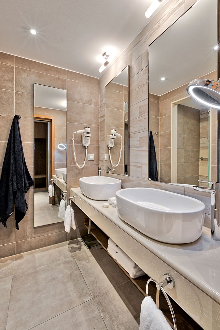 Family garden view room bathroom with dual basins, mirrors, and modern lighting