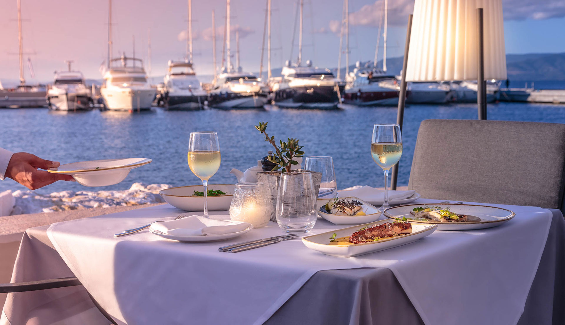 Elegant seaside dinner with gourmet dishes and white wine overlooking the marina