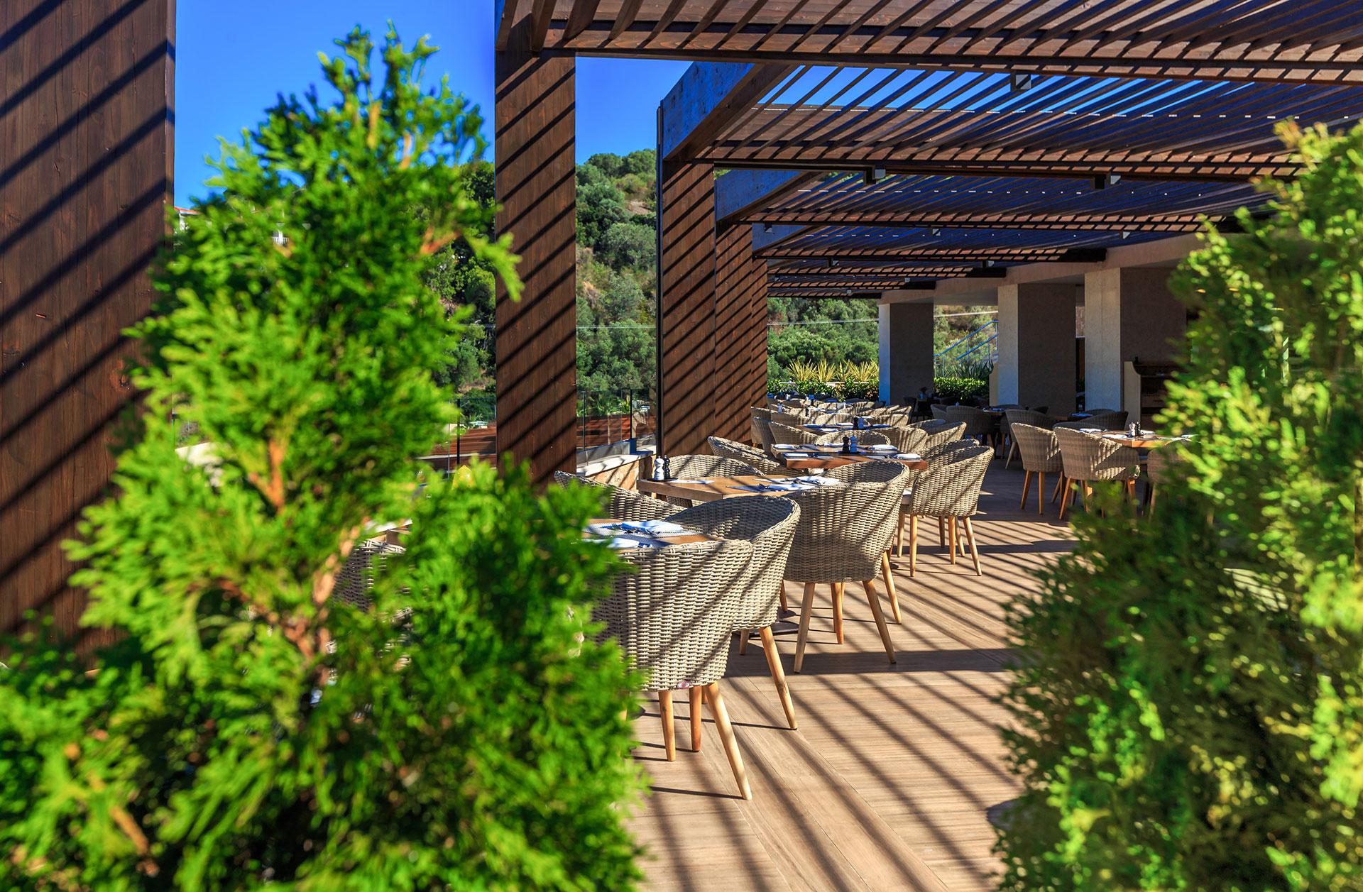 Shaded outdoor dining area with wooden pergola and garden view at Kritamo restaurant