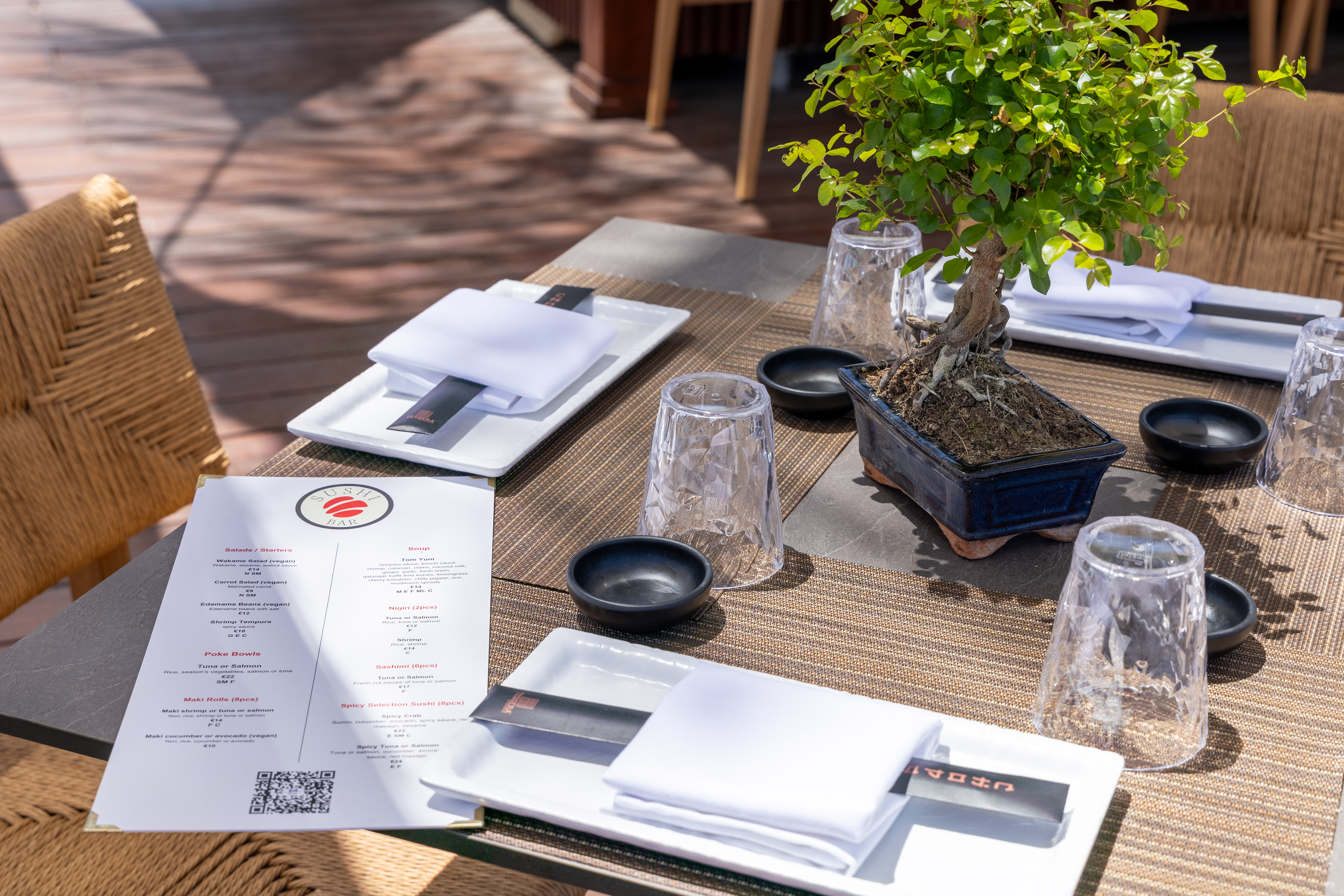 Close-up of elegant sushi bar table setup with bonsai centerpiece and menu
