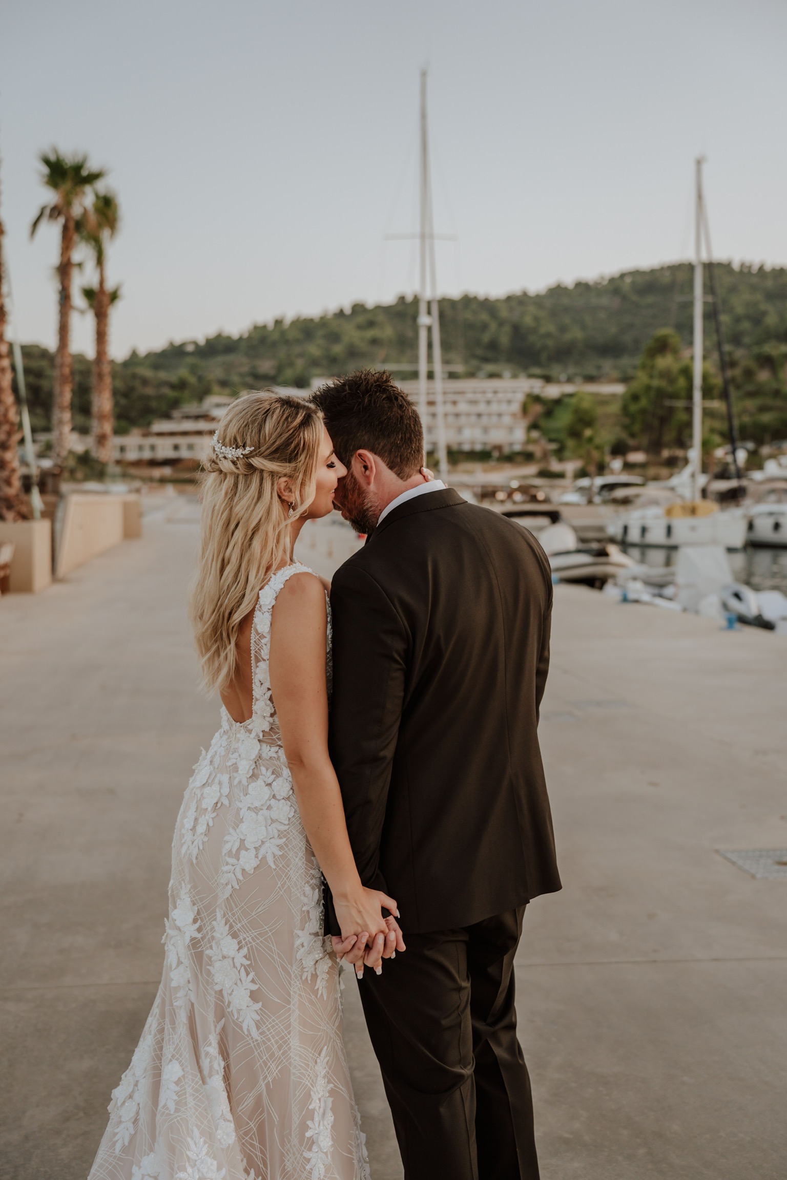 Bride and groom sharing an intimate moment by the marina at sunset