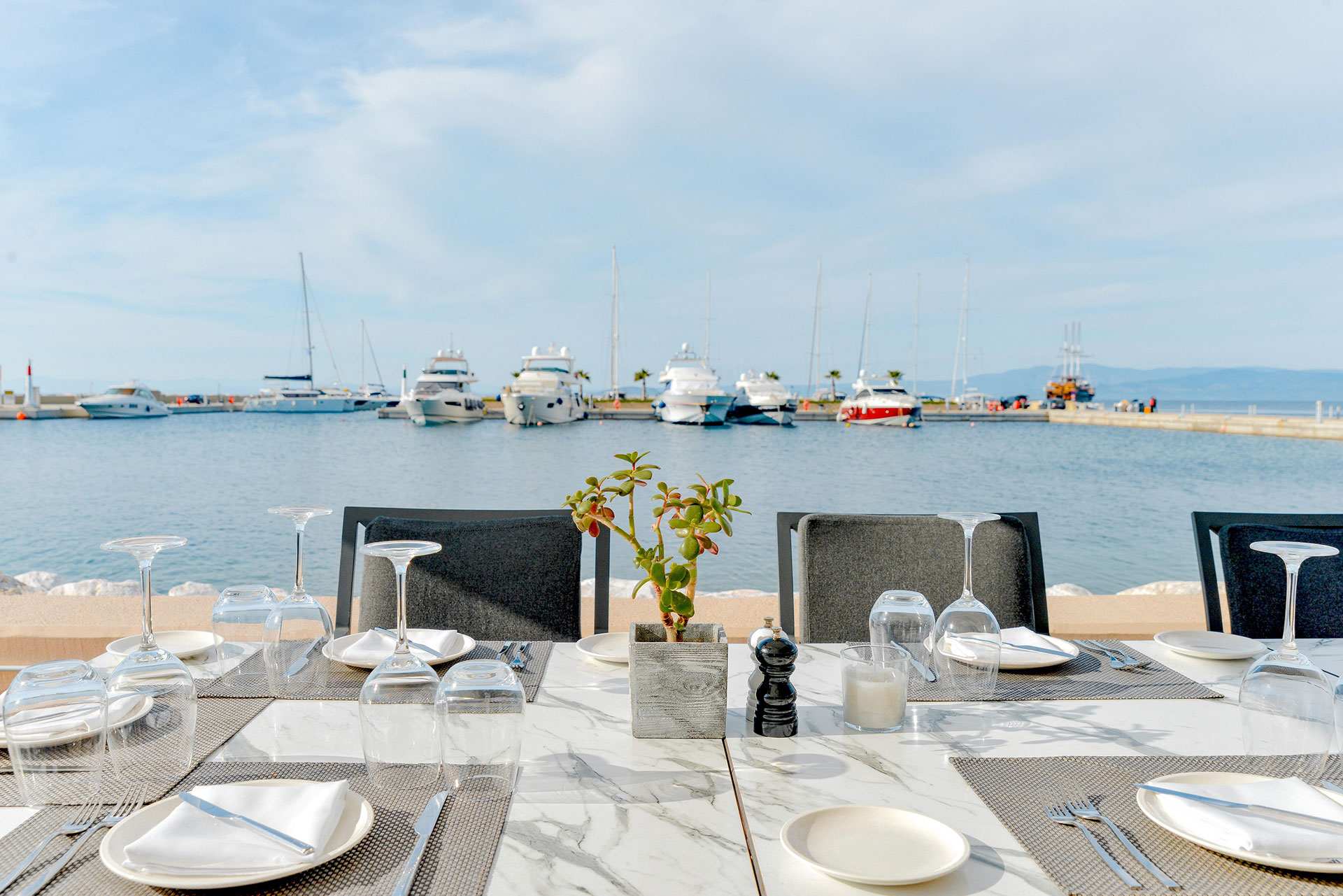 Table set for lunch with marina and yachts in the background at Toroneo restaurant