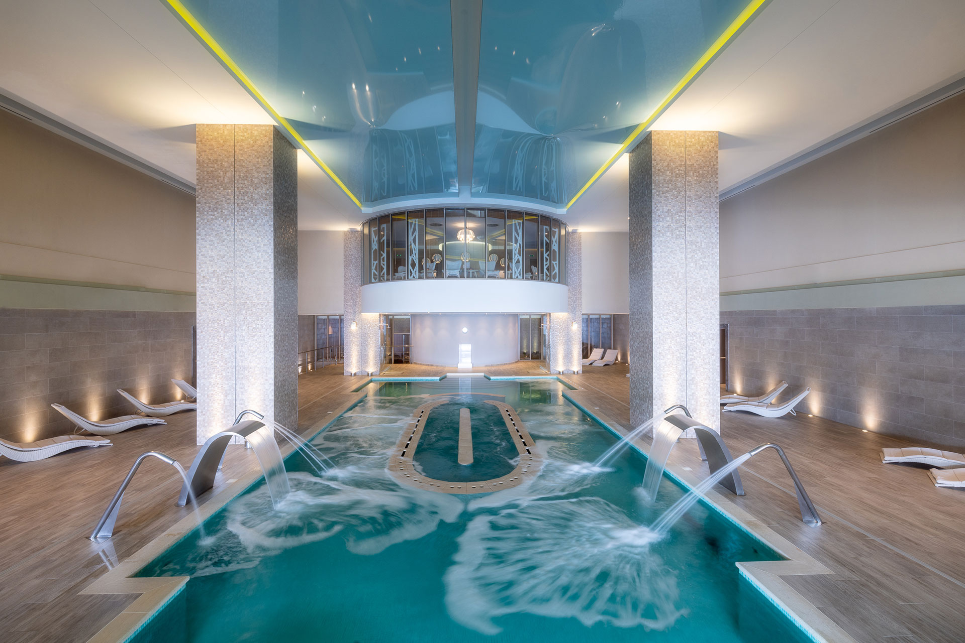 Luxury indoor hydrotherapy pool with cascading water jets and lounge chairs