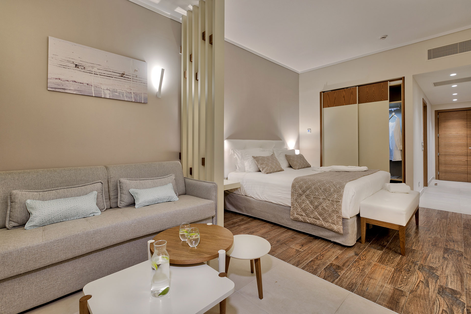 Family room with open-plan layout, king-size bed, sofa area, and warm wooden floors