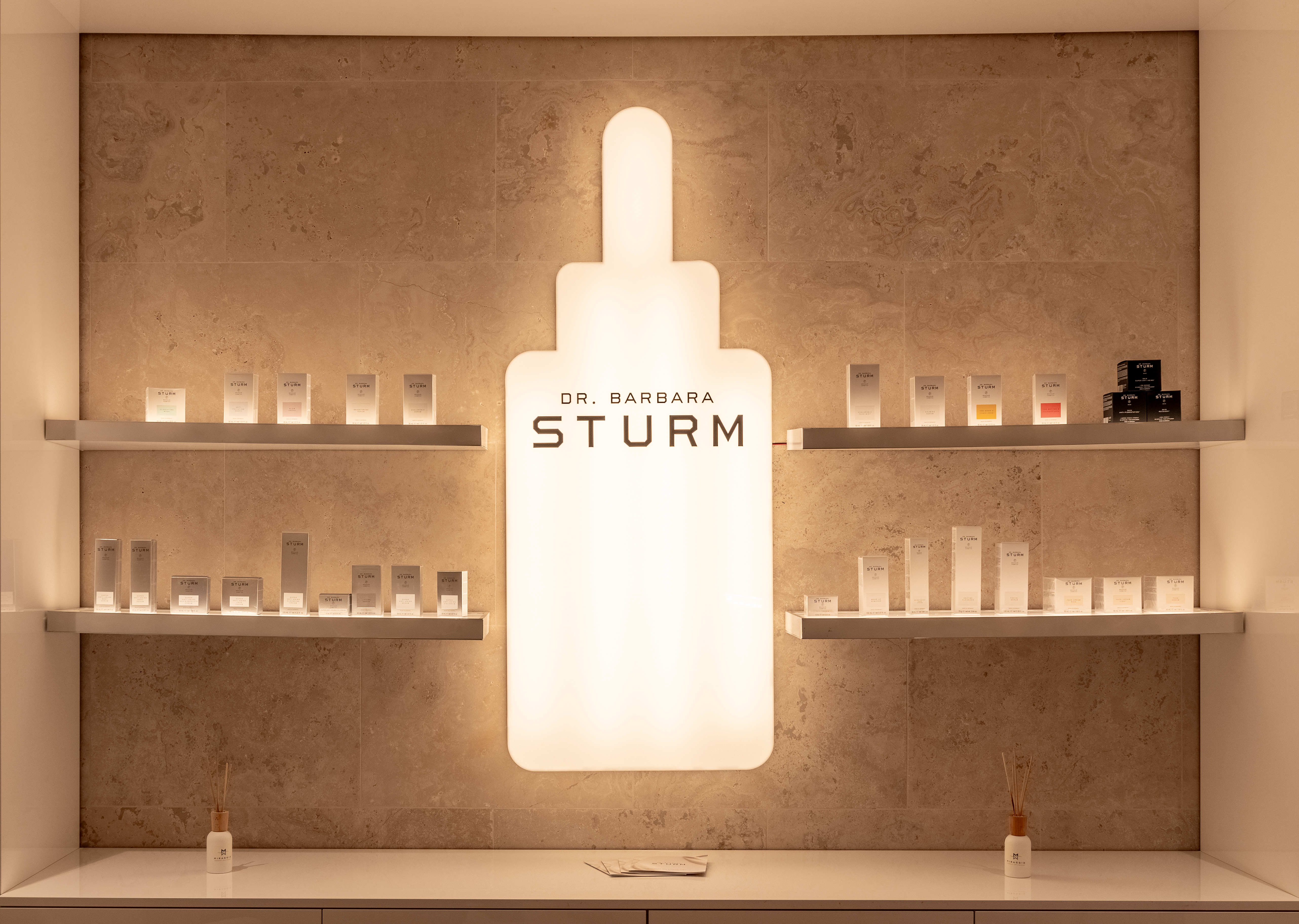 Display shelf with premium Dr Barbara Sturm skincare products and illuminated logo sign