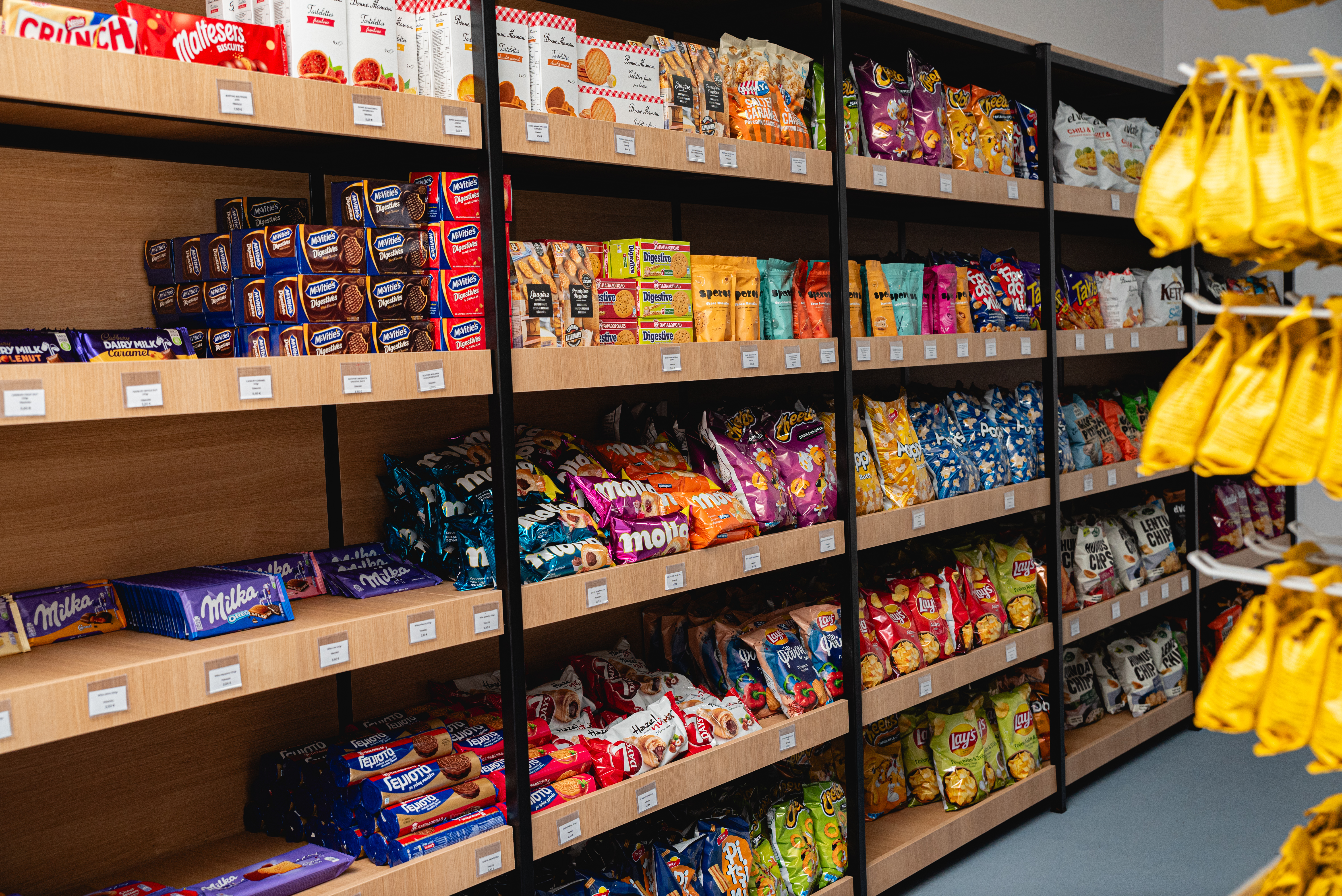 Aisle with neatly organized chips, cookies, and snacks on wooden shelves inside the Miraggio Resort mini market