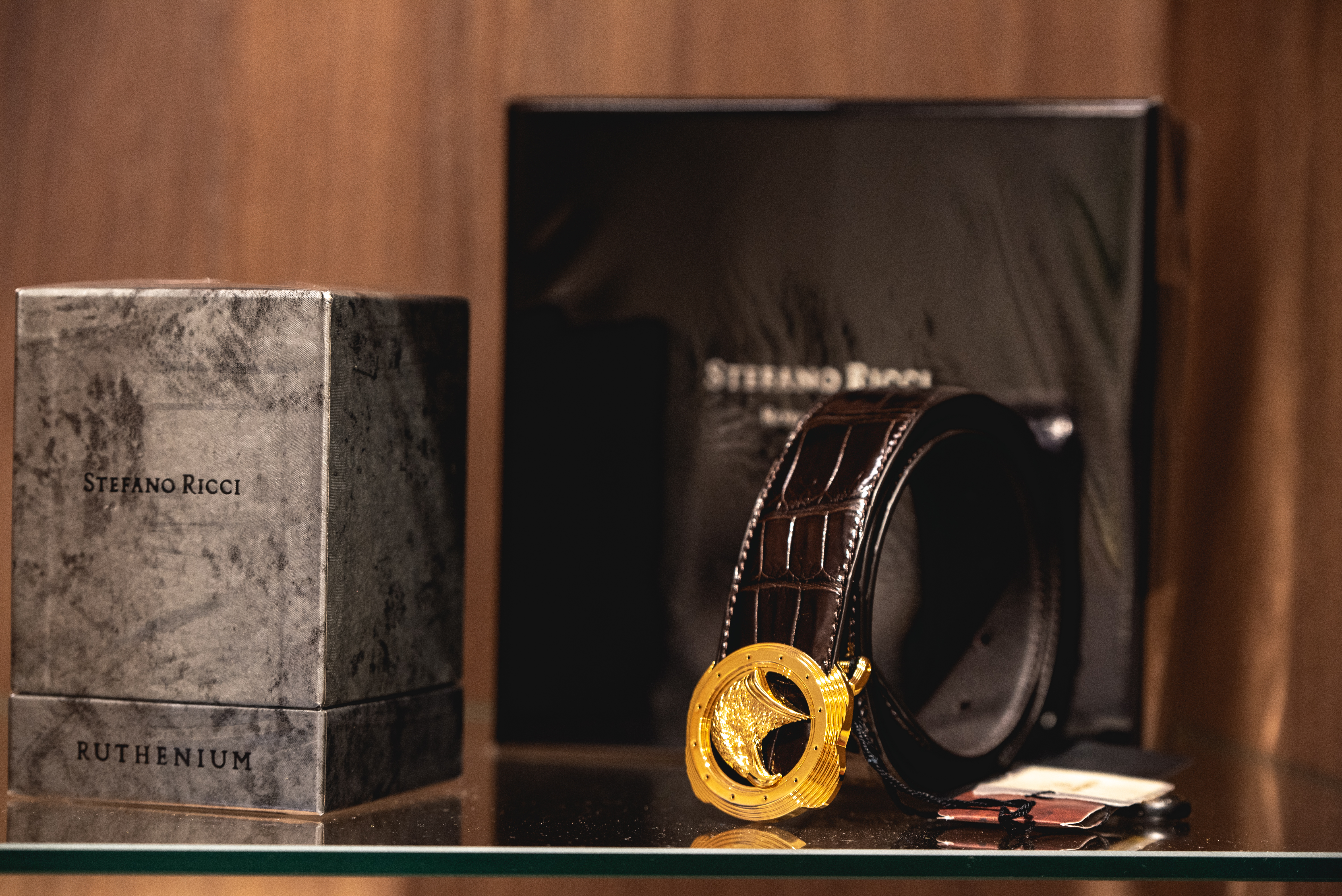 Luxury Stefano Ricci belt with gold buckle displayed beside branded box