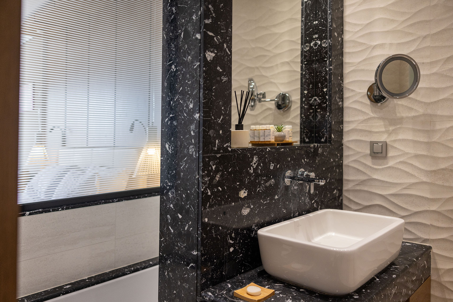 Deluxe bathroom with marble countertop and wall, vanity mirror and elegant basin