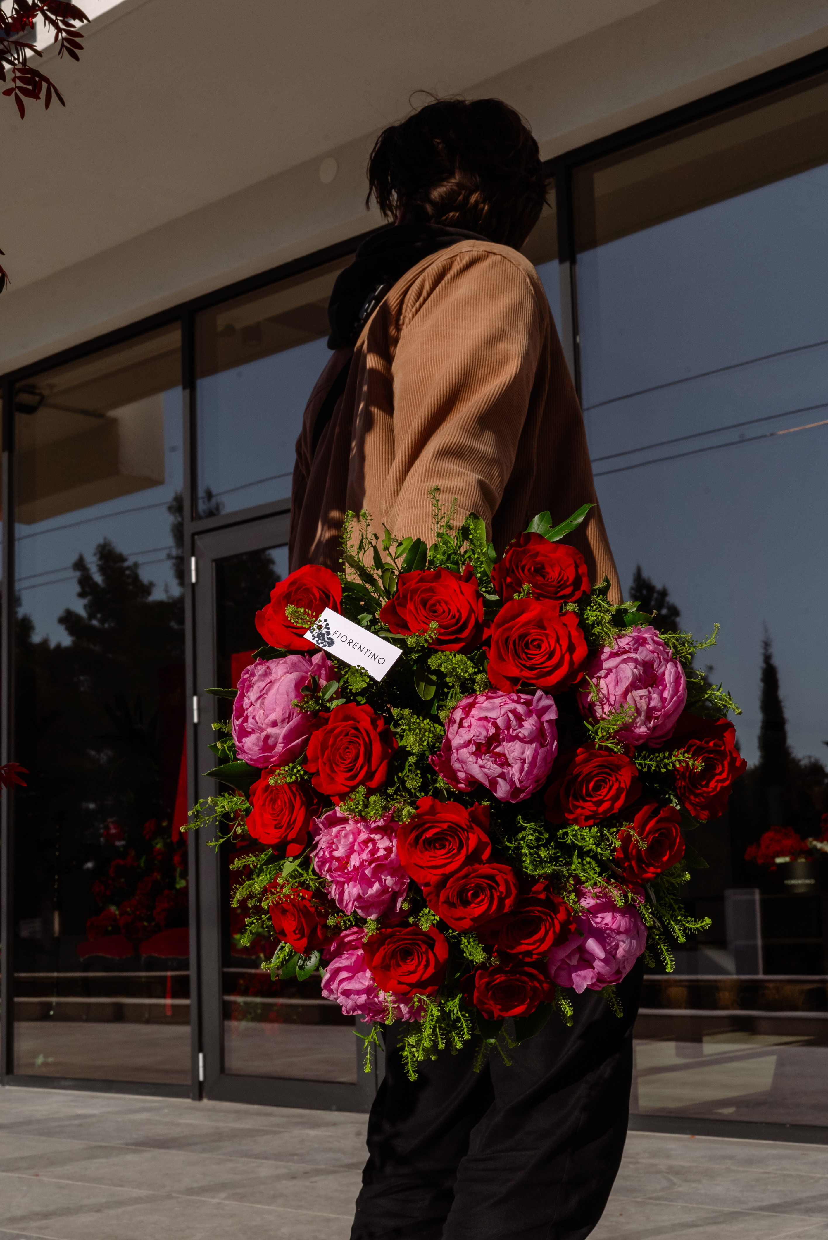 Boy holding bouquet of roses behind his back with Fiorentino tag visible