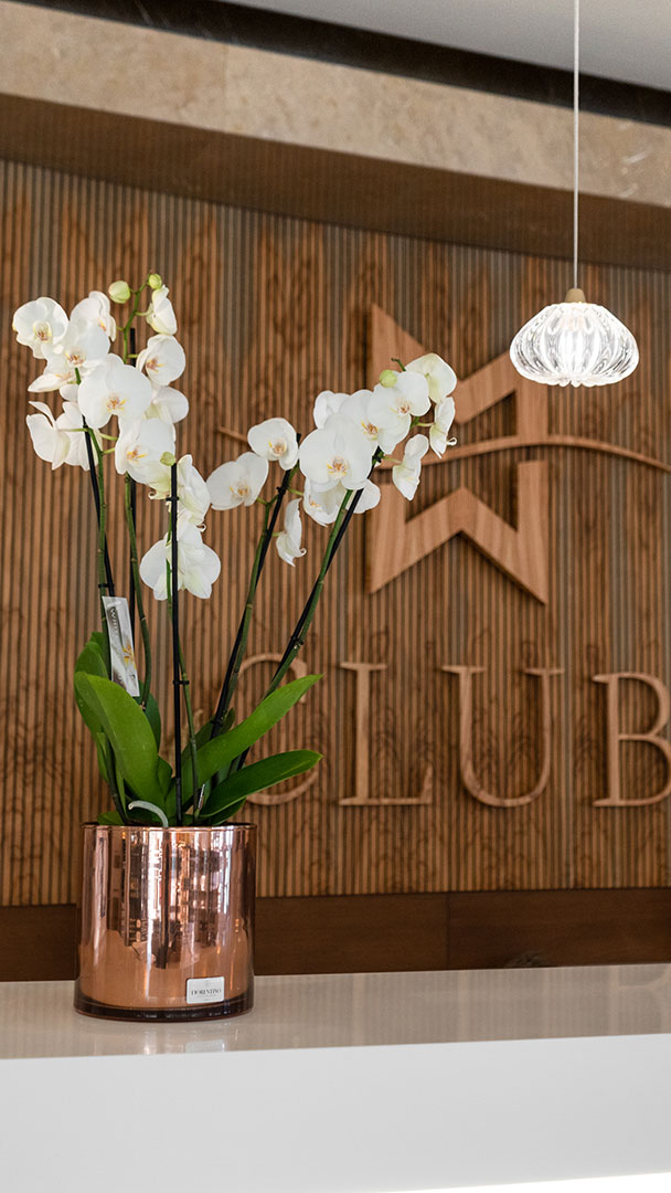 Elegant orchid arrangement in a copper vase on Club reception counter