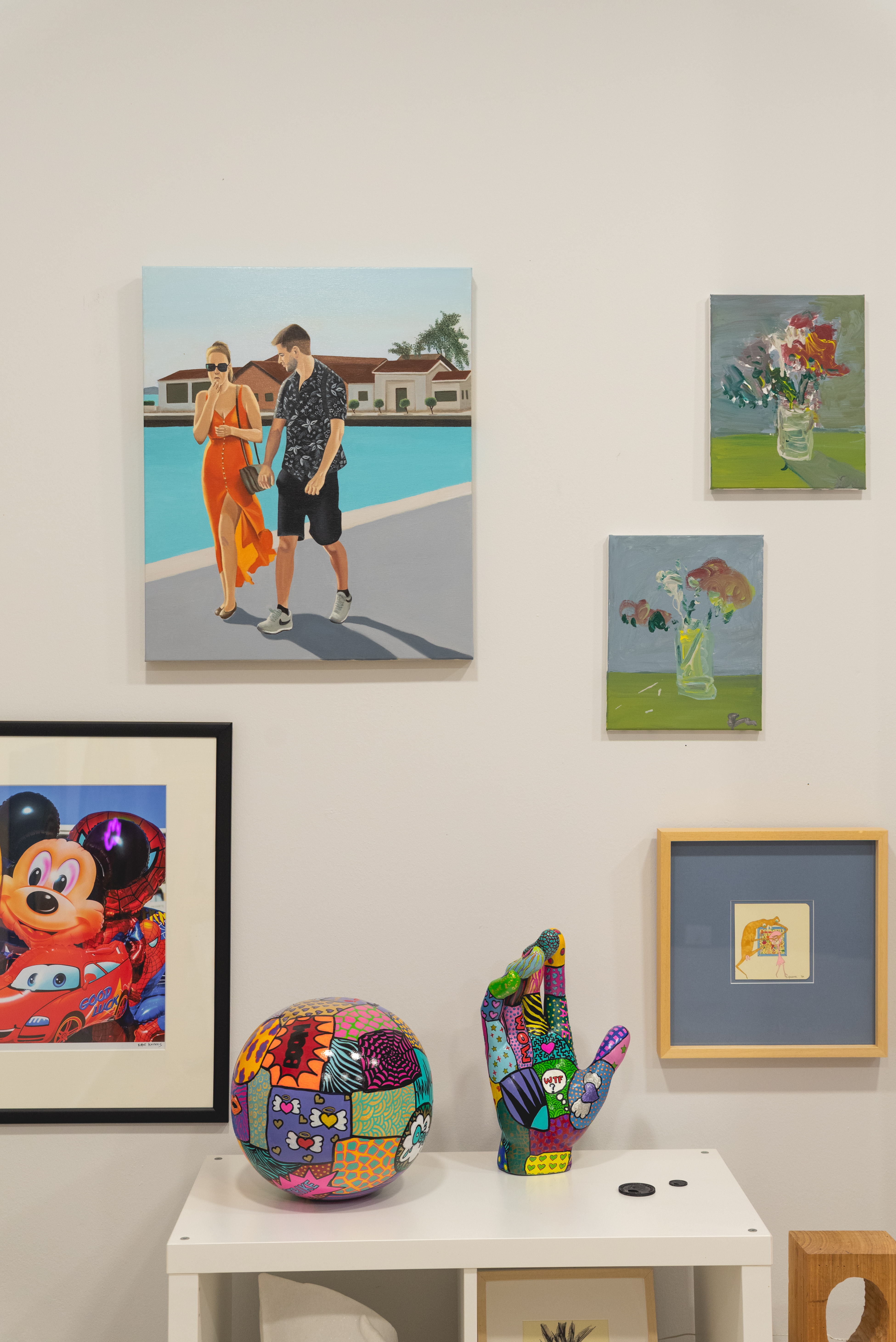 Colorful decorative hand and sphere sculptures displayed beneath framed photographs