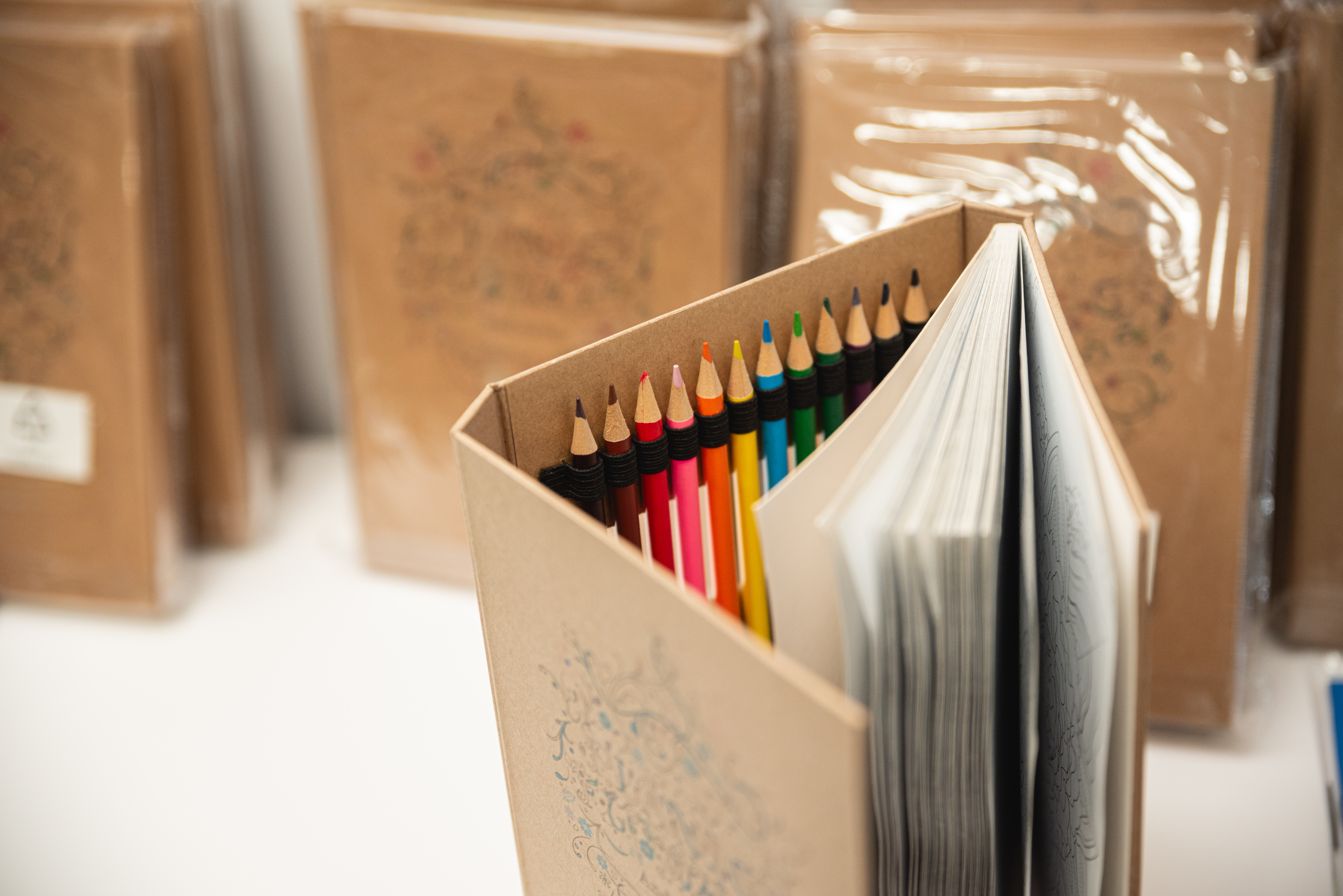 Set of colored pencils neatly arranged beside an open sketchbook with a floral cover