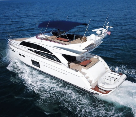 Luxury white flybridge yacht cruising on calm blue waters with shaded upper deck and real tender