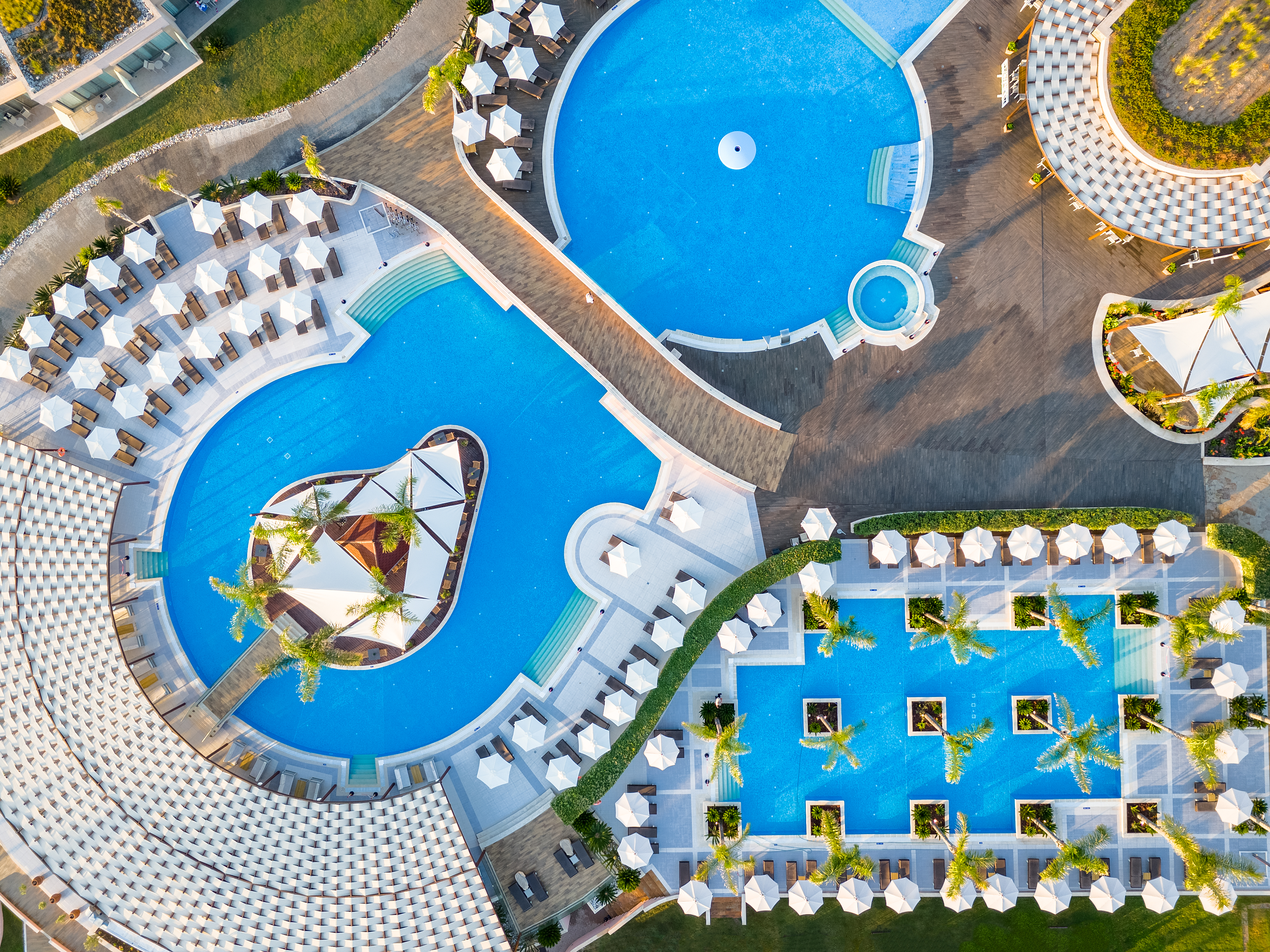 Aerial top-down view of the stunning pool complex with multiple interconnected pools, palm trees and sunbeds 