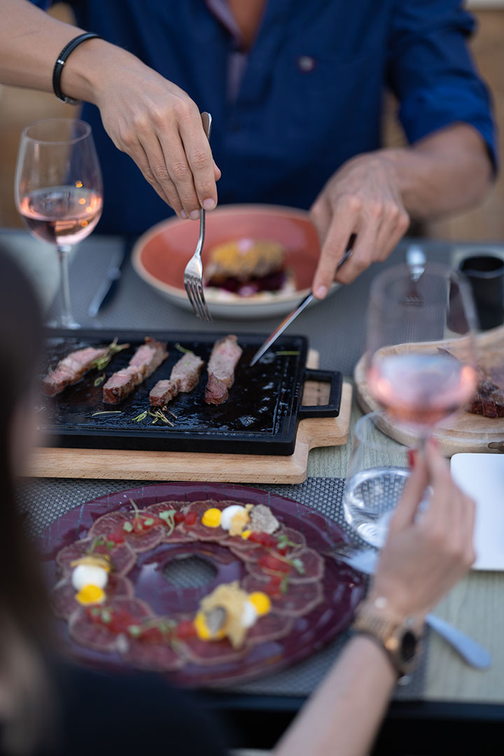 Guest enjoying seared steak slices and fine dining experience at Sommelier's 8 restaurant