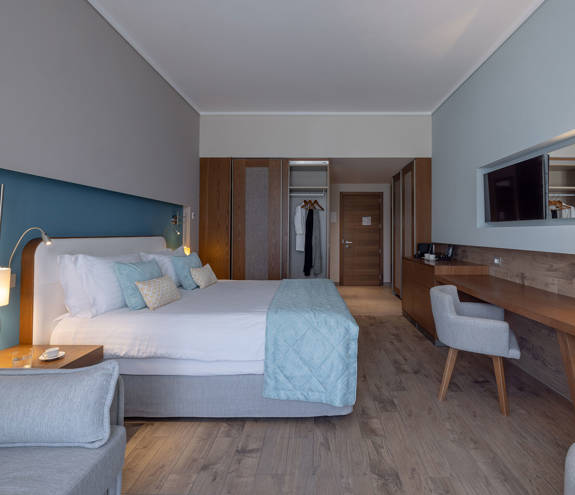 Deluxe Side Sea View entrance, bed, chairs and amenities