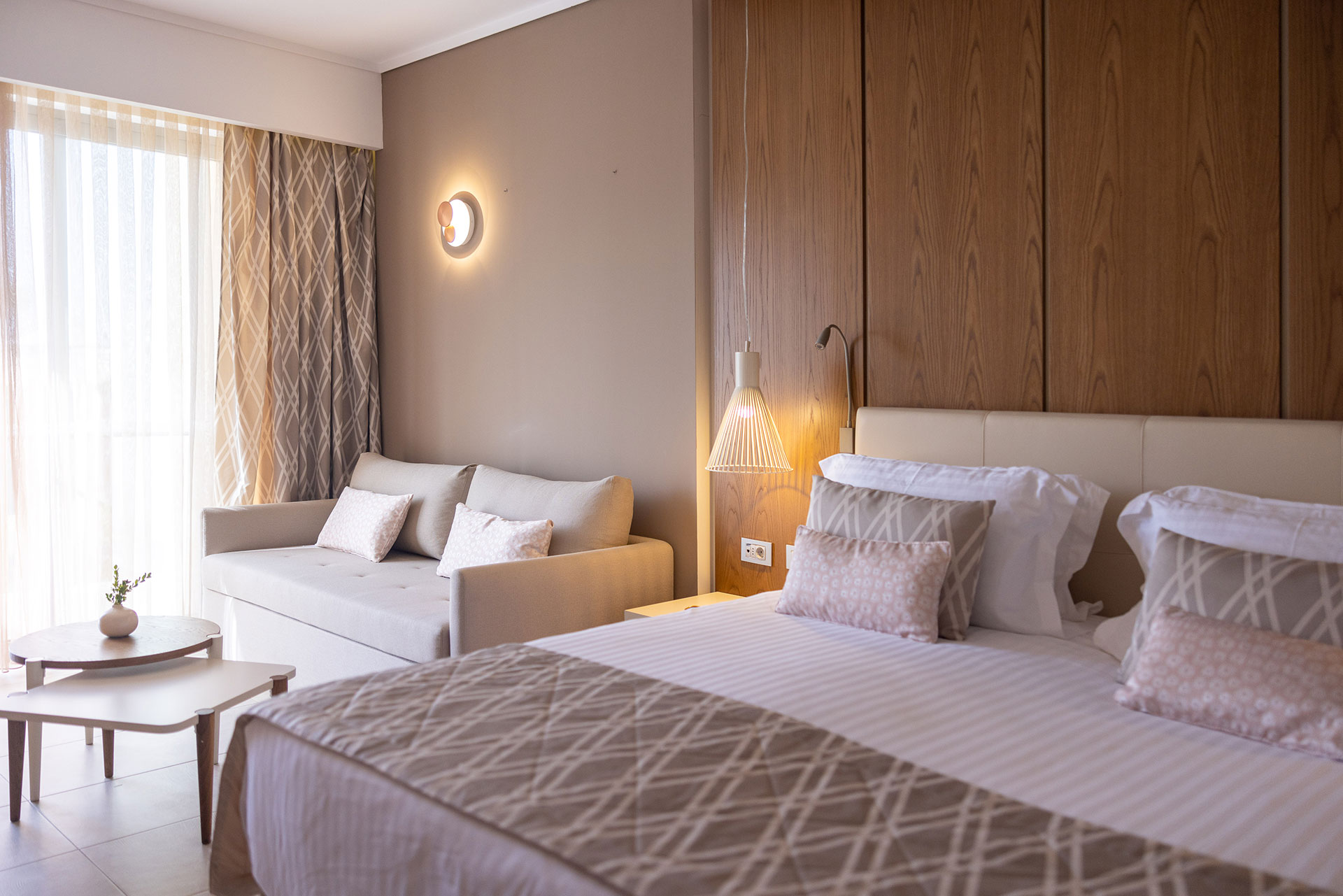 King size bed with wooden modern headboard near the cozy seating area of the deluxe room