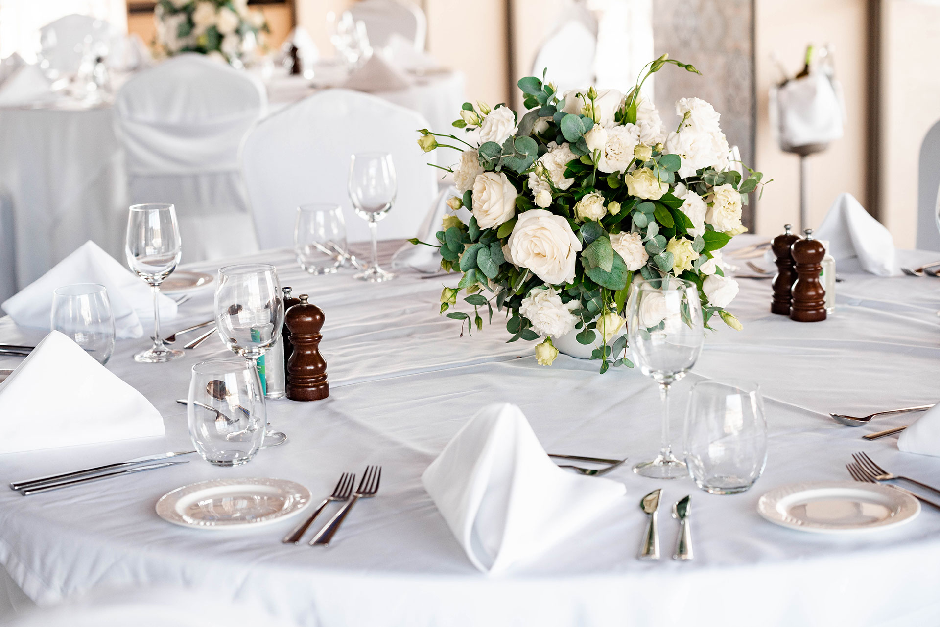 Elegant indoor wedding table setup with white floral centerpiece and glassware