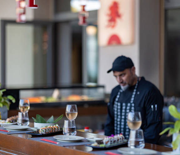 Sushi Bar chef behind the decorated bar with food and wine