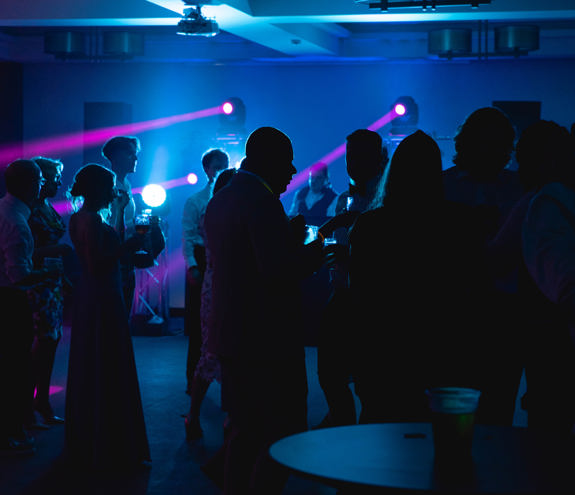 Indoor wedding dance area with guests and soft blue lighting