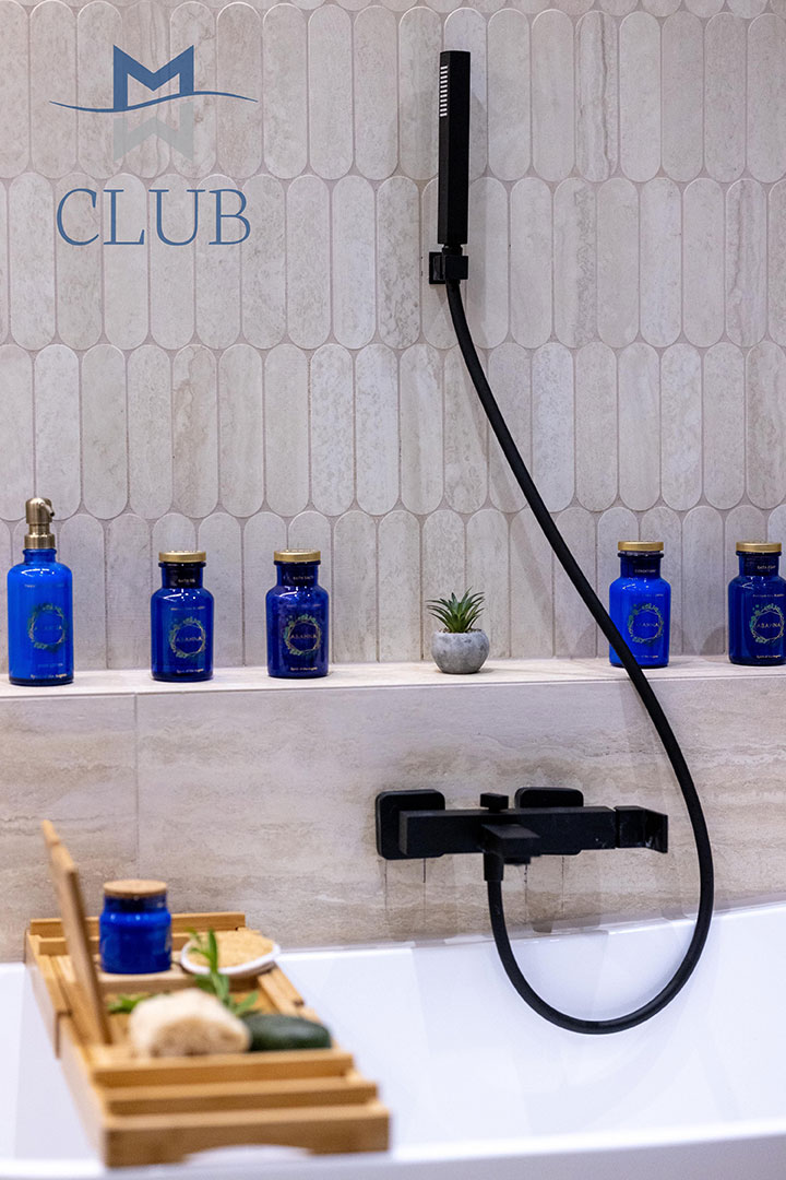 Close up to bathtub's stylish black hand shower, and amenities 
