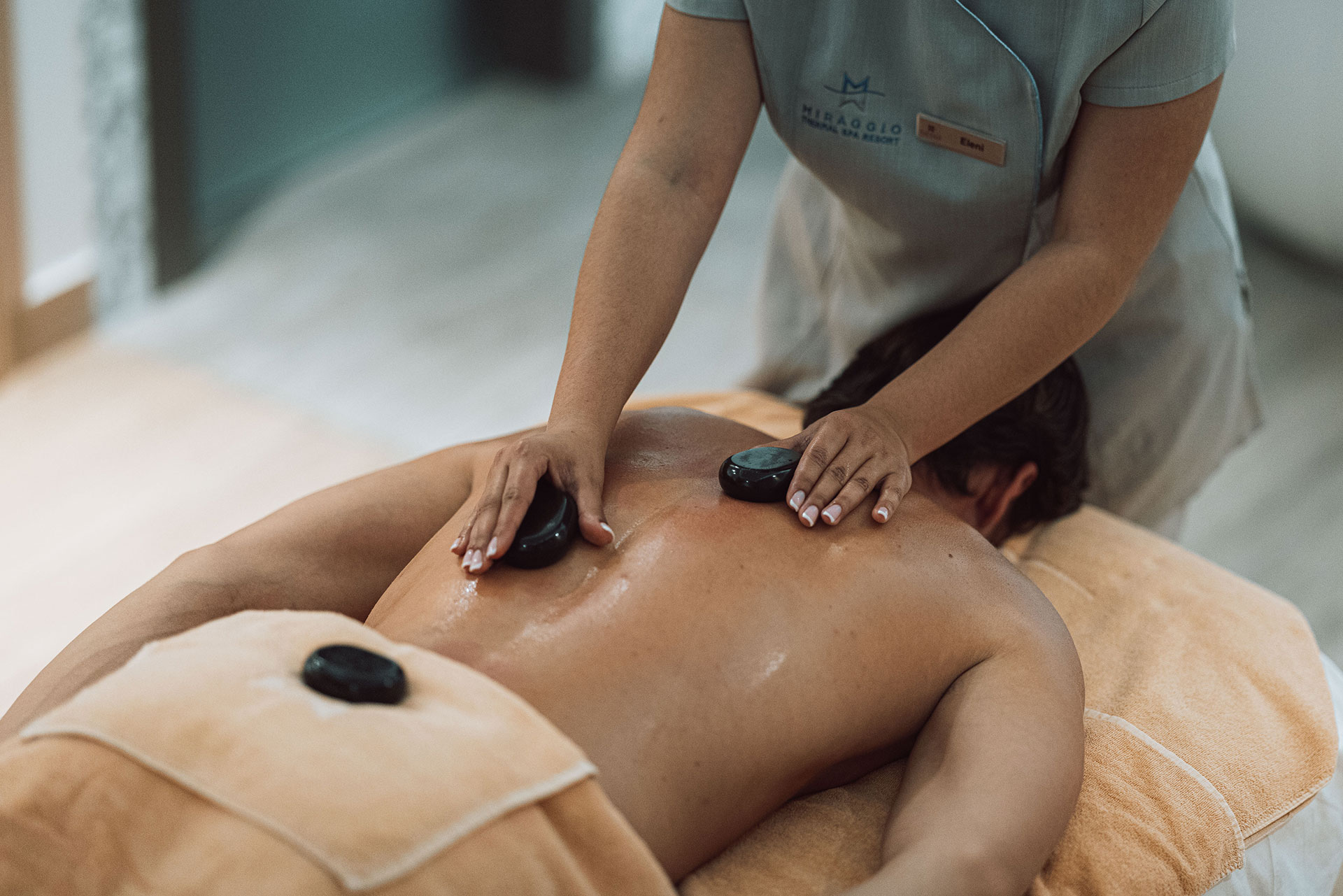 Therapist performing relaxing hot stone massage on guest's back
