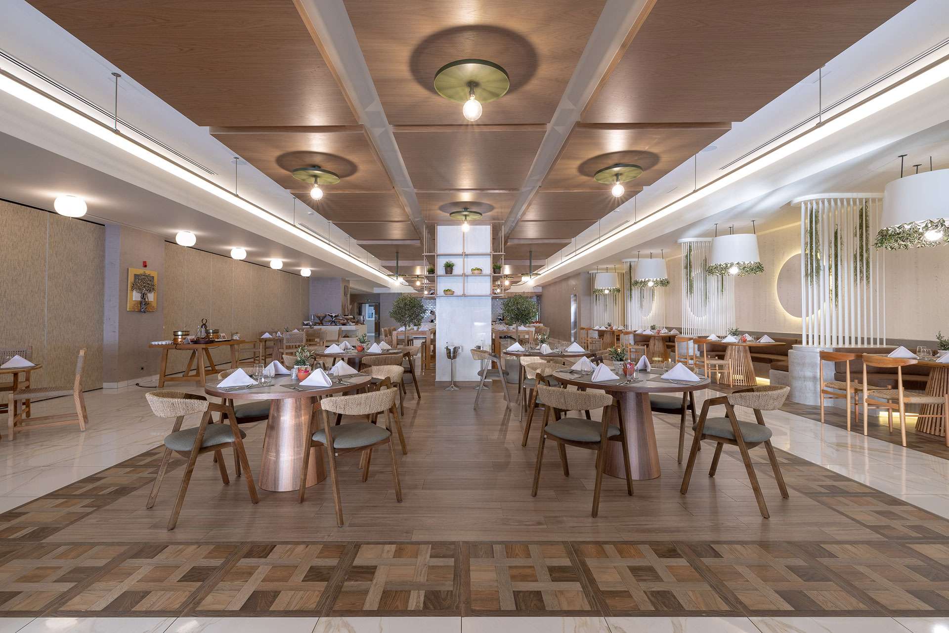 Spacious interior of Elia restaurant featuring wooden accents, warm lighting and elegant table arrangements