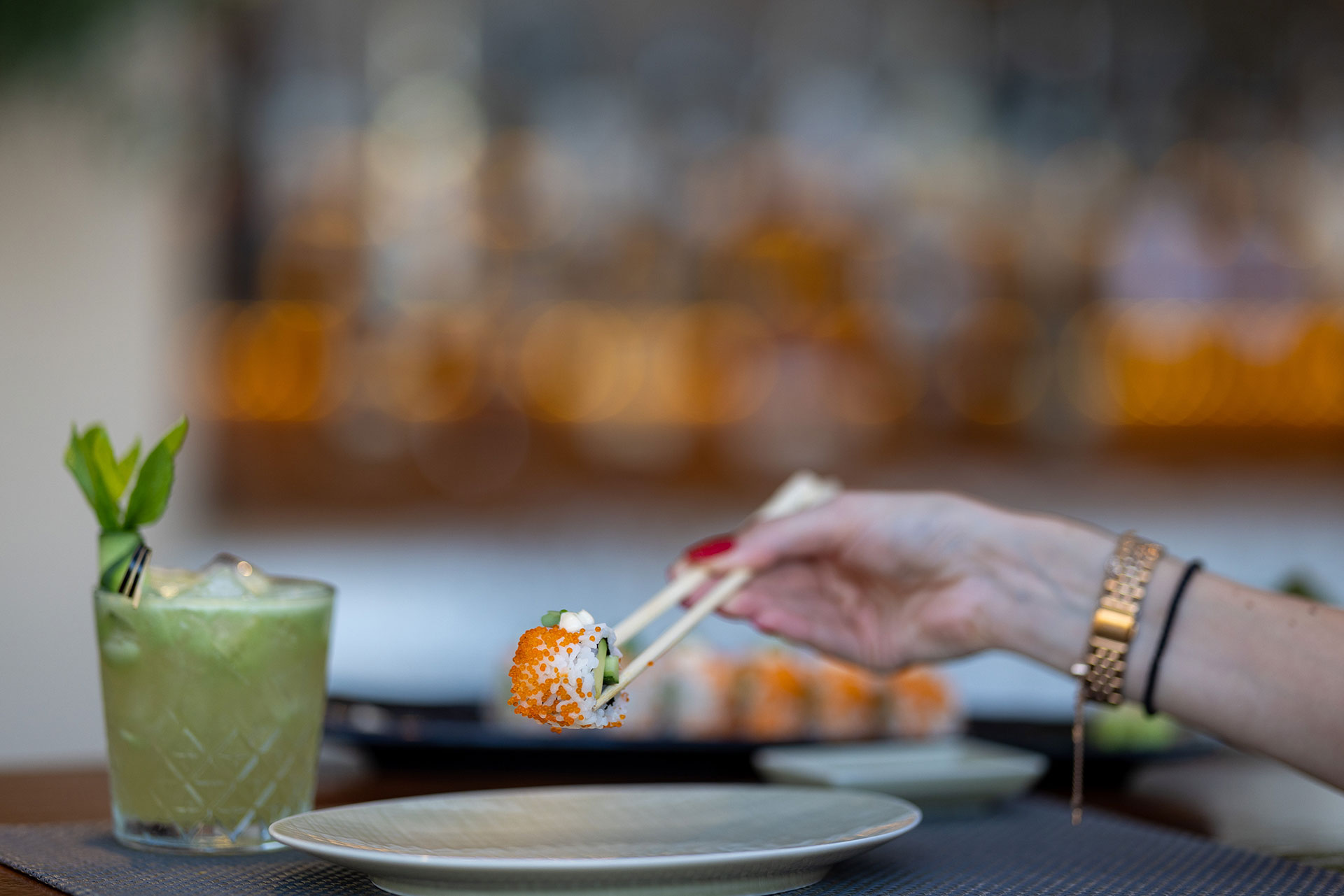 Guest enjoying fresh sushi with chopsticks and a cocktail