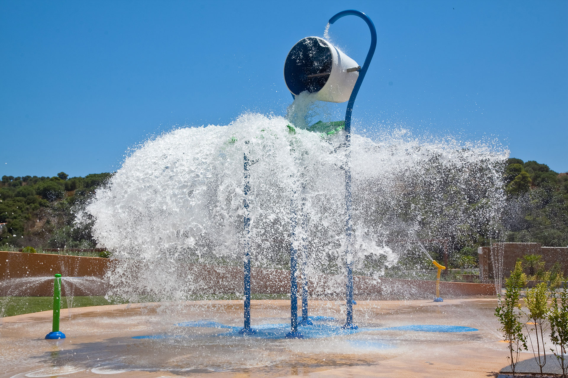 Large tipping bucket splashing water at the outdoor aqua play area in Kids Planet