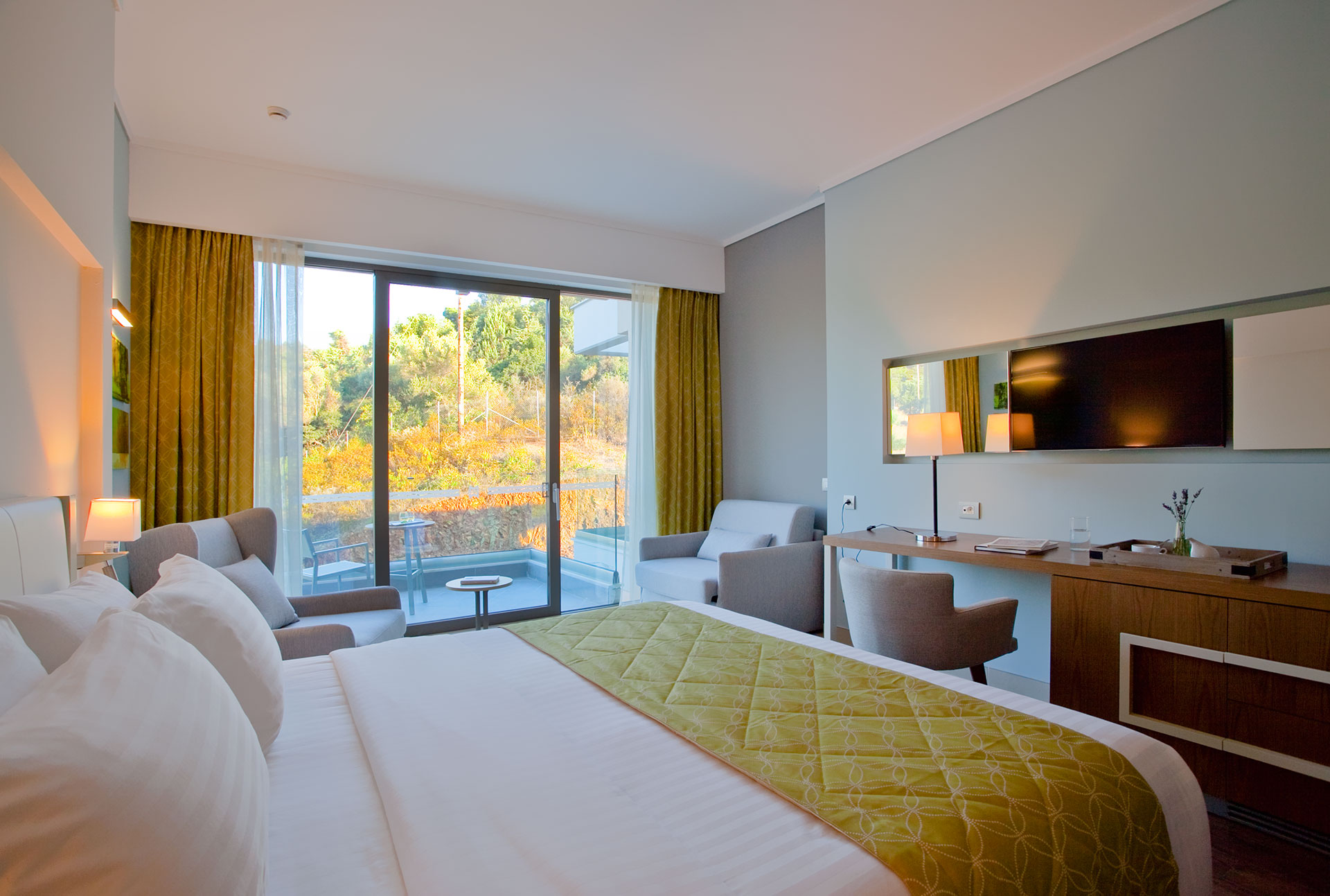 Superior room with king bed, modern decor and private terrace overlooking lush greenery